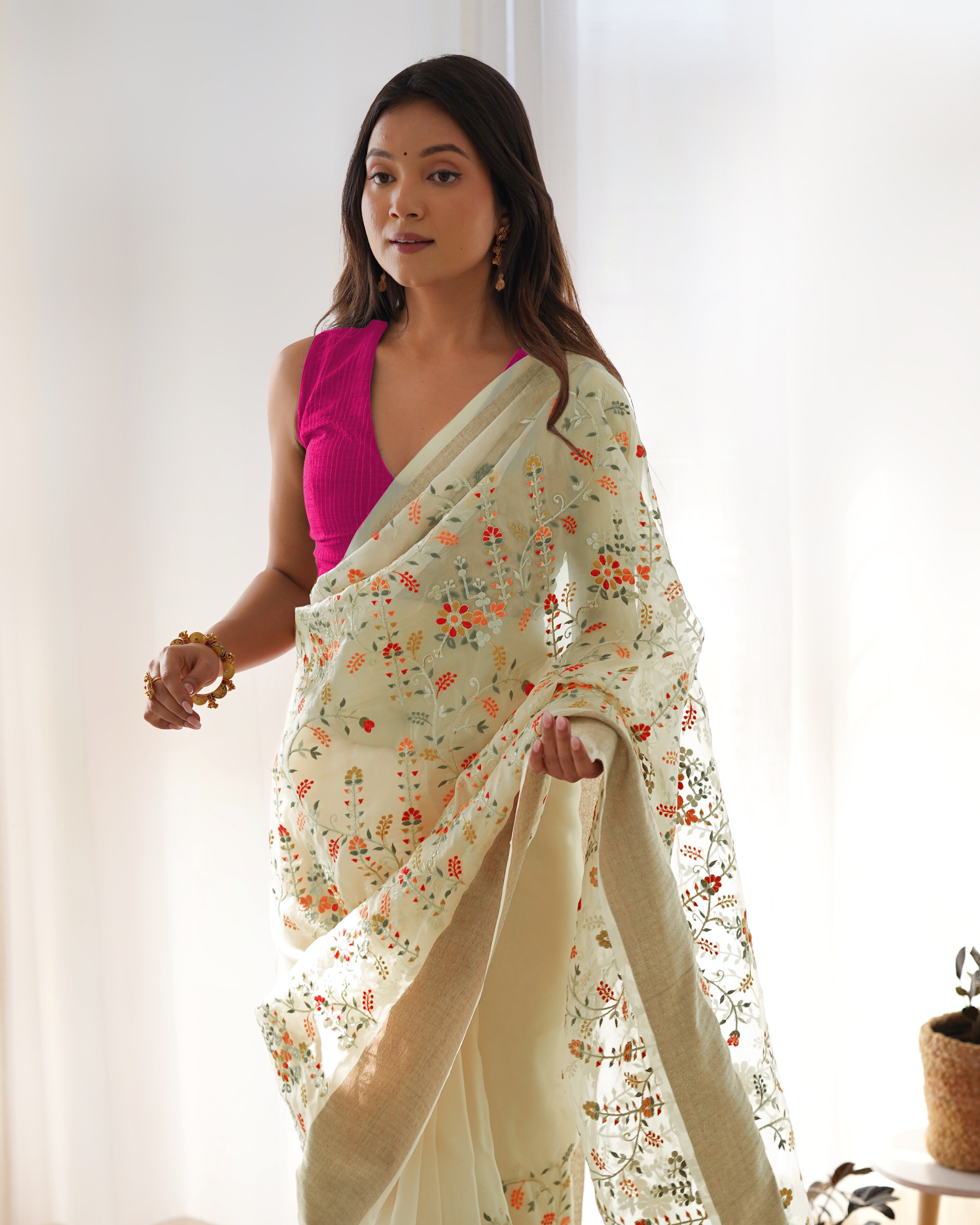 Cream pure organza silk saree with multicolor floral embroidery and solid pink blouse worn by a model