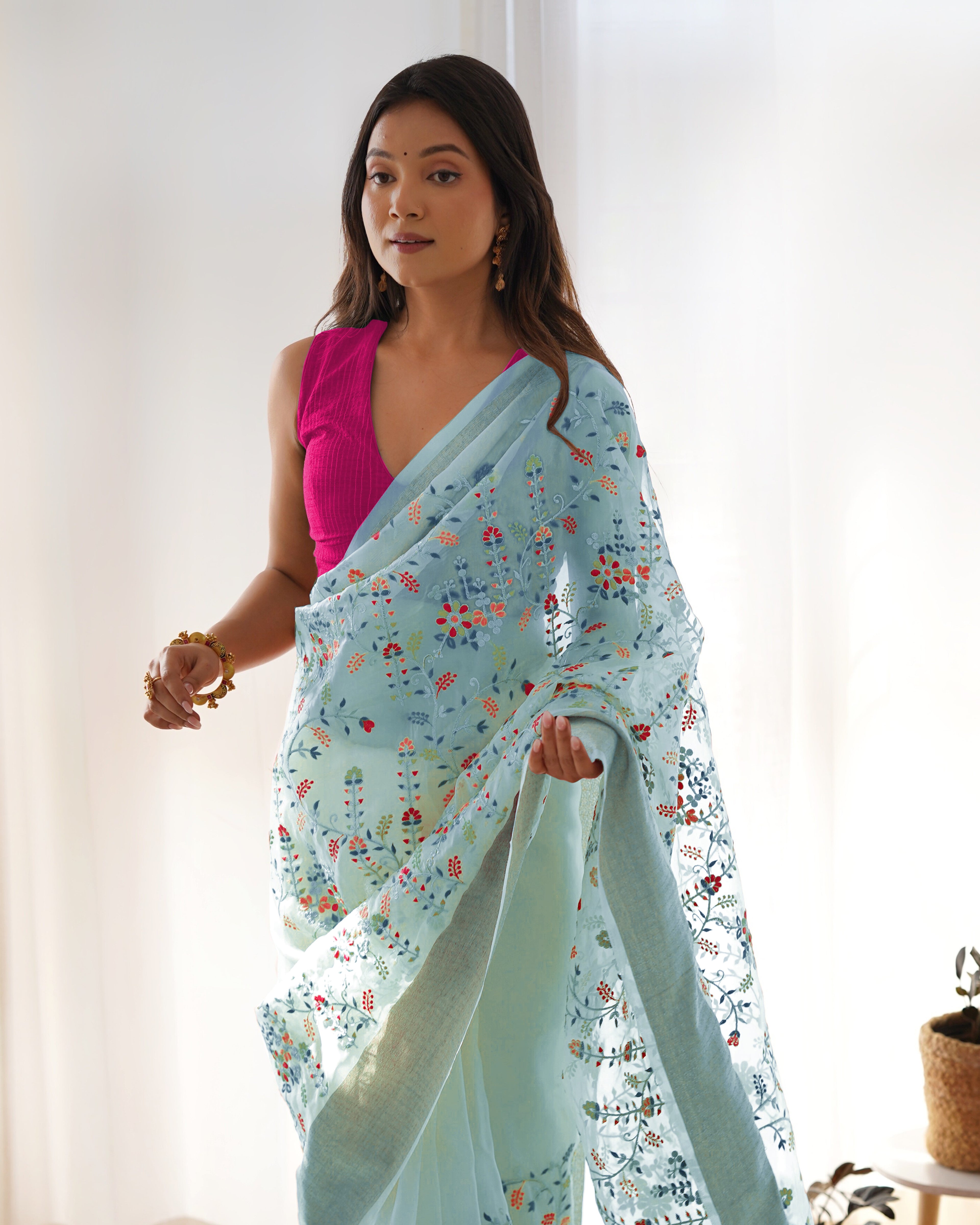 Cream pure organza silk saree with multicolor floral embroidery and solid pink blouse worn by a model