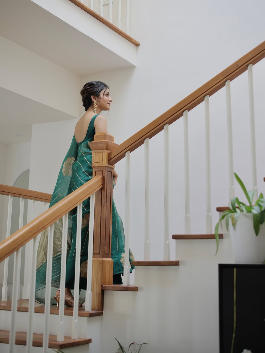 Woman in a green dress standing on a staircase indoors