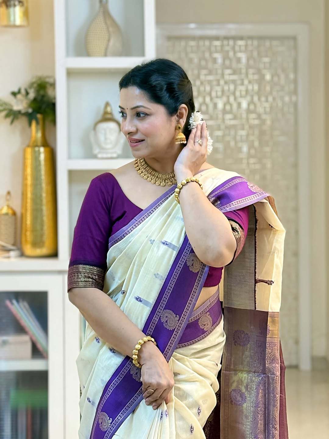 Woman in a traditional saree with a purple blouse in an indoor setting