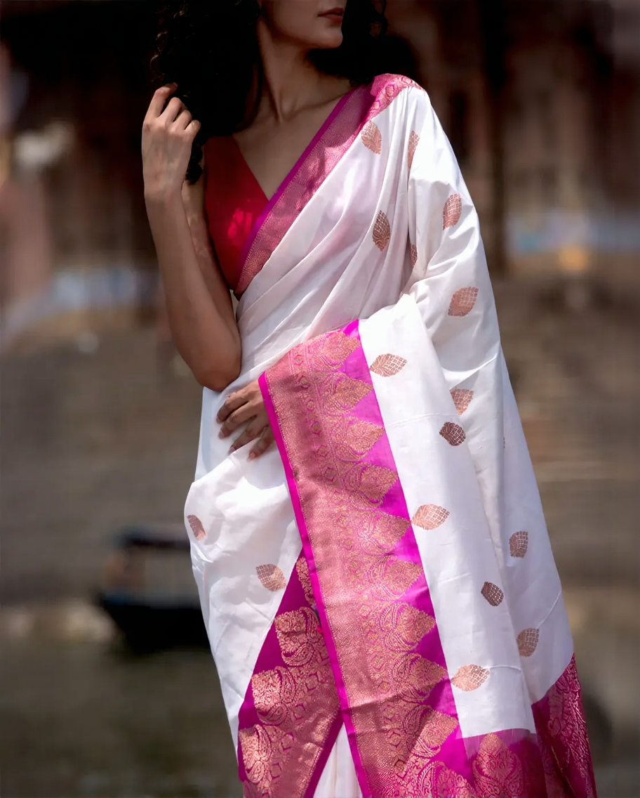 White saree with pink border worn by a person, blurred background