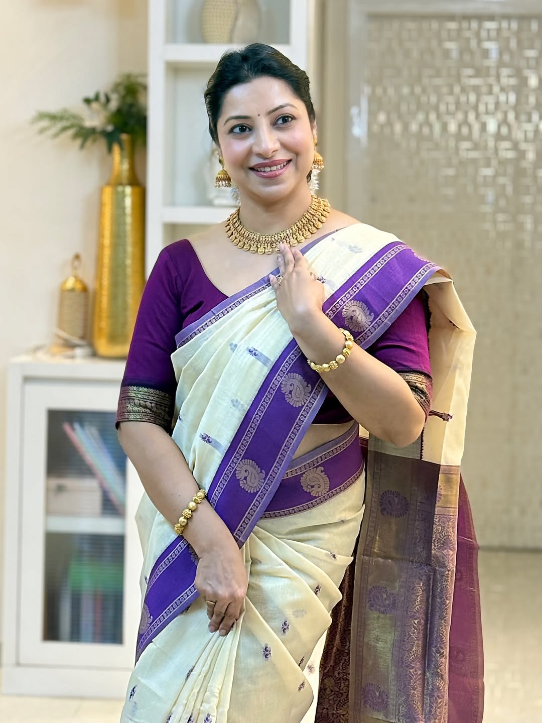 Woman in a traditional saree with a purple blouse in an indoor setting