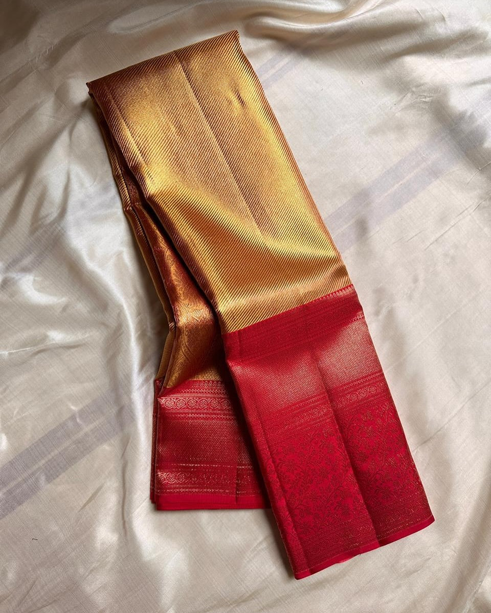 Radiant gold Banarasi Silk saree with a shimmering self-weave pattern, featuring a bold classic red border and pallu intricately woven with dense gold zari floral and ornamental motifs, elegantly draped.