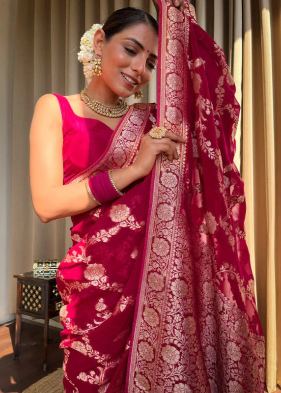 Woman in a traditional pink saree with gold patterns indoors
