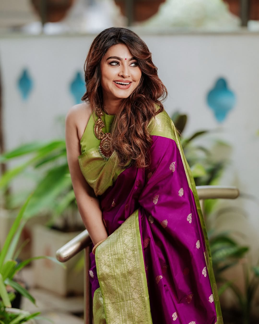 Woman wearing a purple and green saree with a decorative background