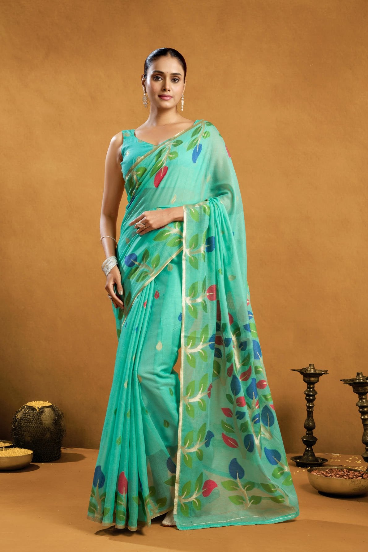 A Pure Cotton Spun Saree featuring exquisite all-over floral Jamdani weaving. The saree is accompanied by a running blouse piece detailed with all-over leaf weave butties and a matching border, available as a six-piece set.