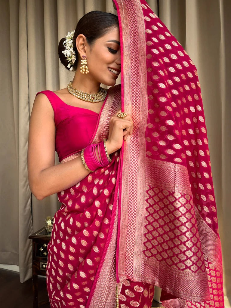 Woman in a pink saree with a matching blouse, holding the pallu against a neutral background.