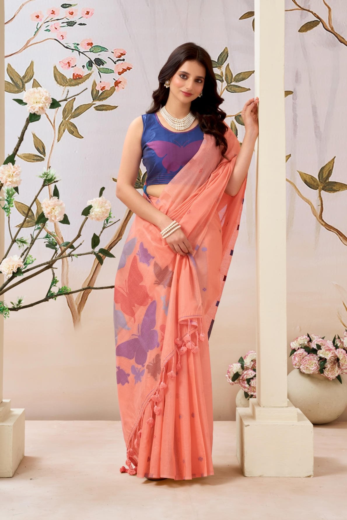 A Pure Mul Cotton Handloom Saree (6.30 meters) featuring a lightweight drape, adorned with all-over delicate flower weave butties. The contrast blouse (0.80 meters) is crafted from Pure Mul Cotton and highlighted by a single large, intricate butterfly weave, sold as a six-piece set.