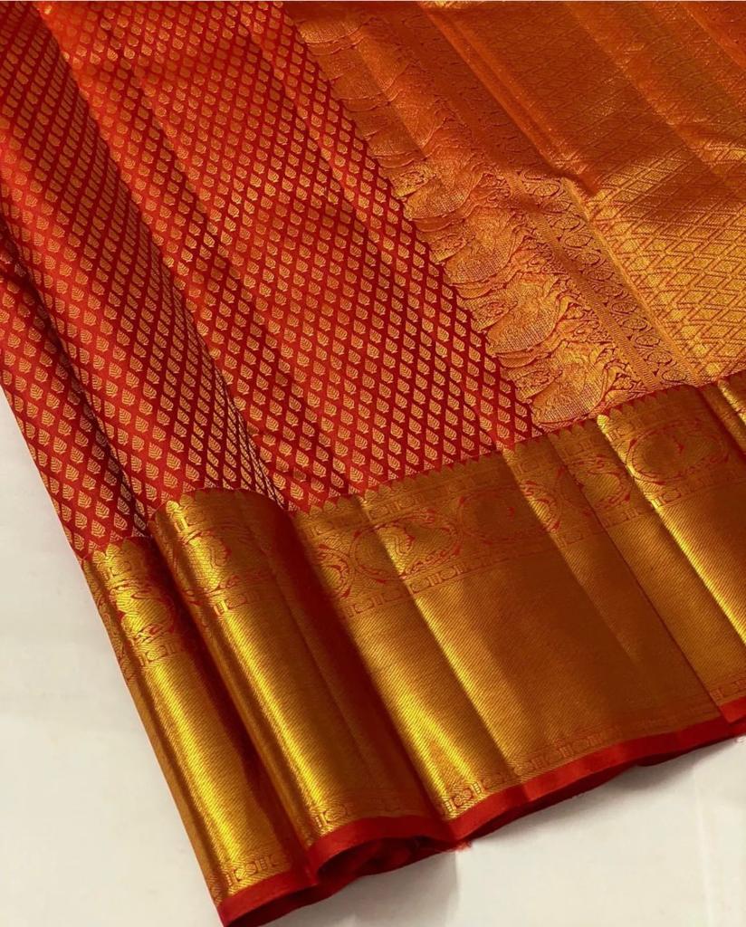 Orange and gold traditional fabric with intricate patterns on a white background