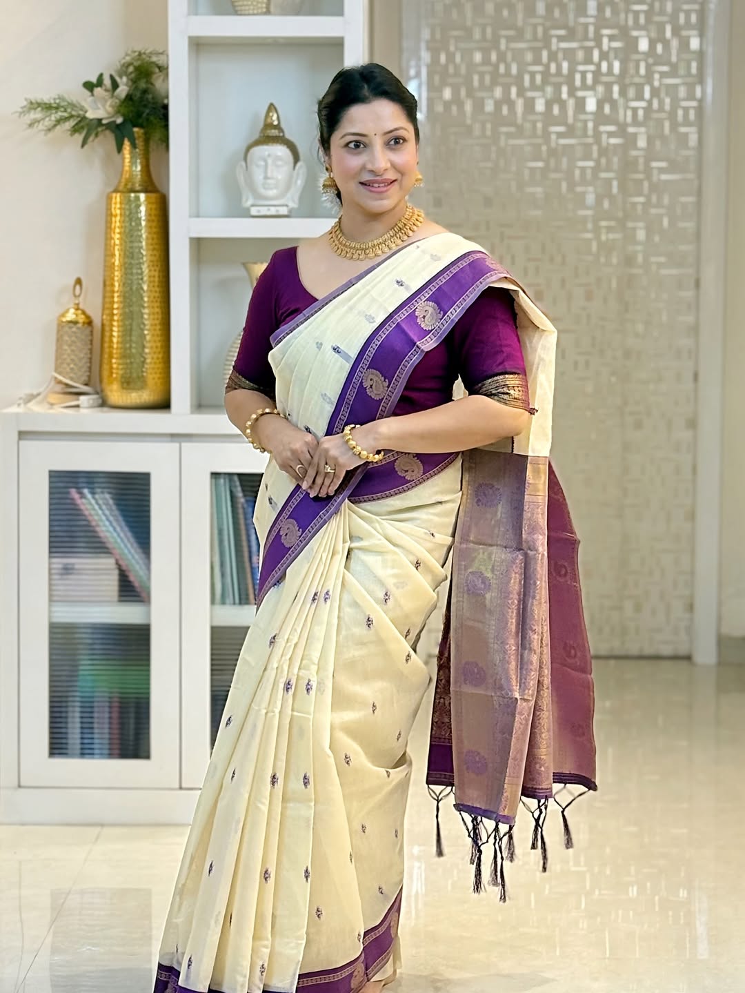 Woman wearing a white and purple saree in an indoor setting