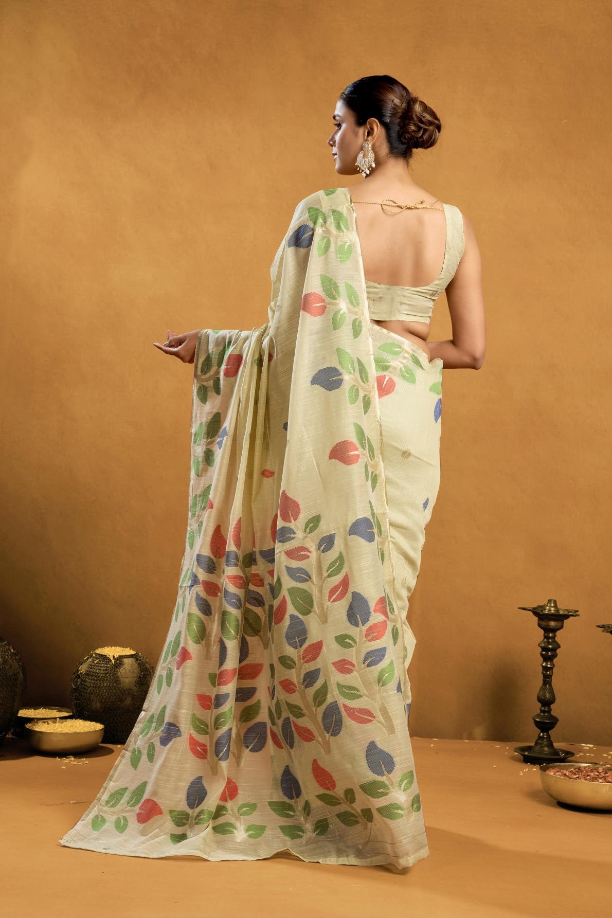 A Pure Cotton Spun Saree featuring exquisite all-over floral Jamdani weaving. The saree is accompanied by a running blouse piece detailed with all-over leaf weave butties and a matching border, available as a six-piece set.