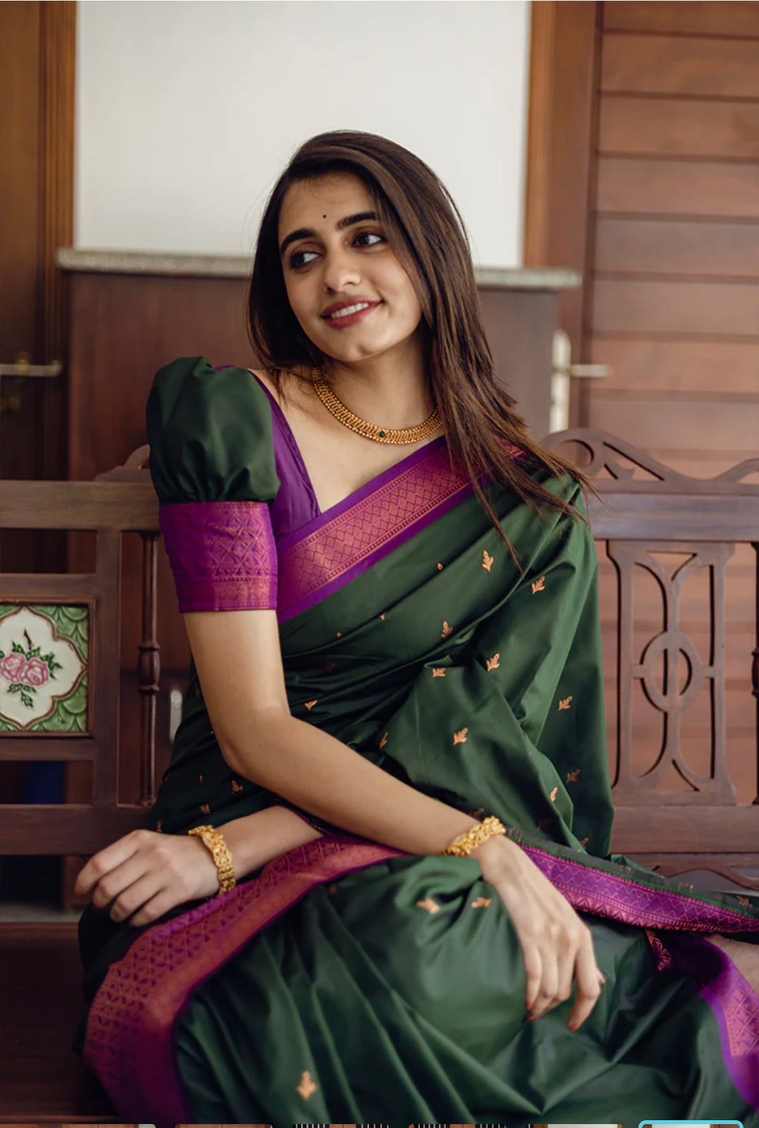 Deep forest green Banarasi Silk saree with small gold zari buttis and a striking magenta contrast border, worn by a model in an outdoor setting.