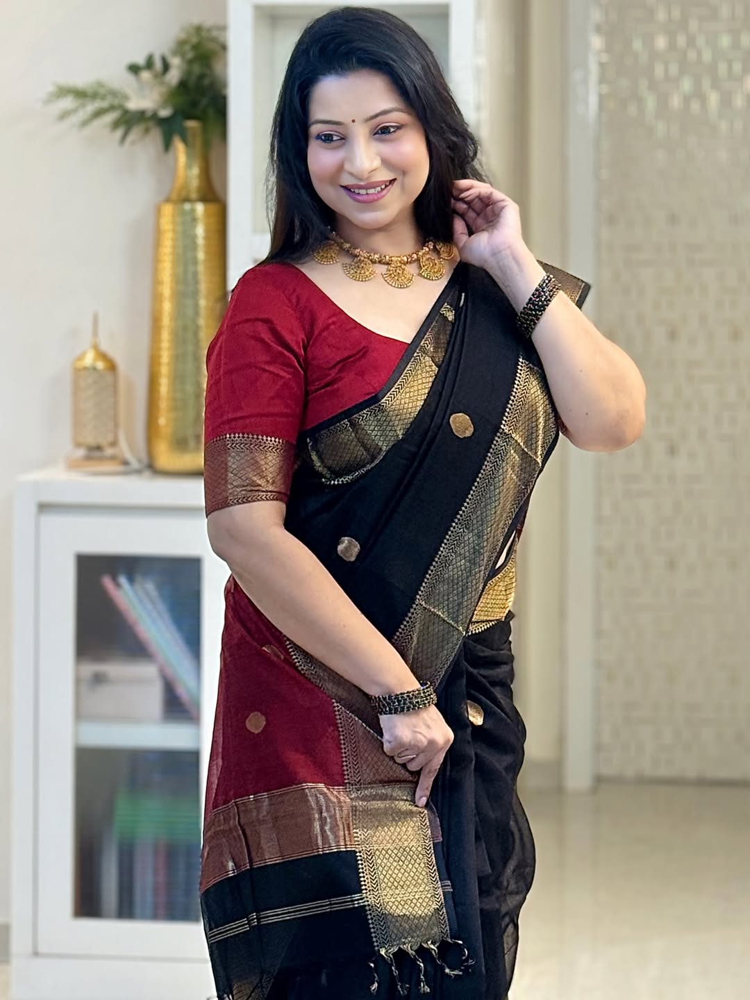 Woman wearing a traditional saree with a red blouse in an indoor setting