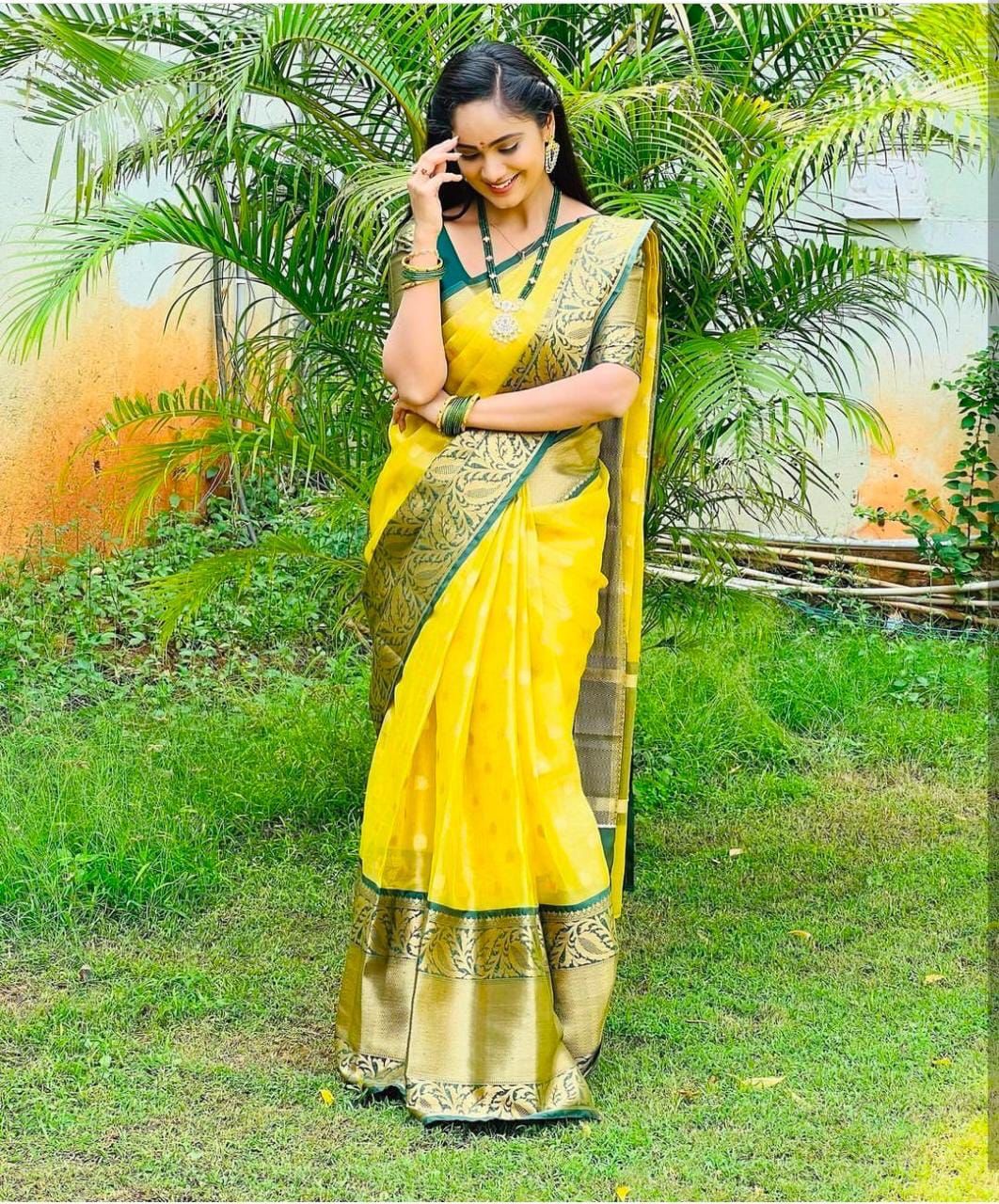 Bright yellow Banarasi Silk saree with wide, deep green and gold zari woven contrast border and pallu, featuring traditional motifs.