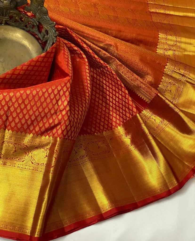 Orange and gold traditional fabric with intricate patterns on a white background