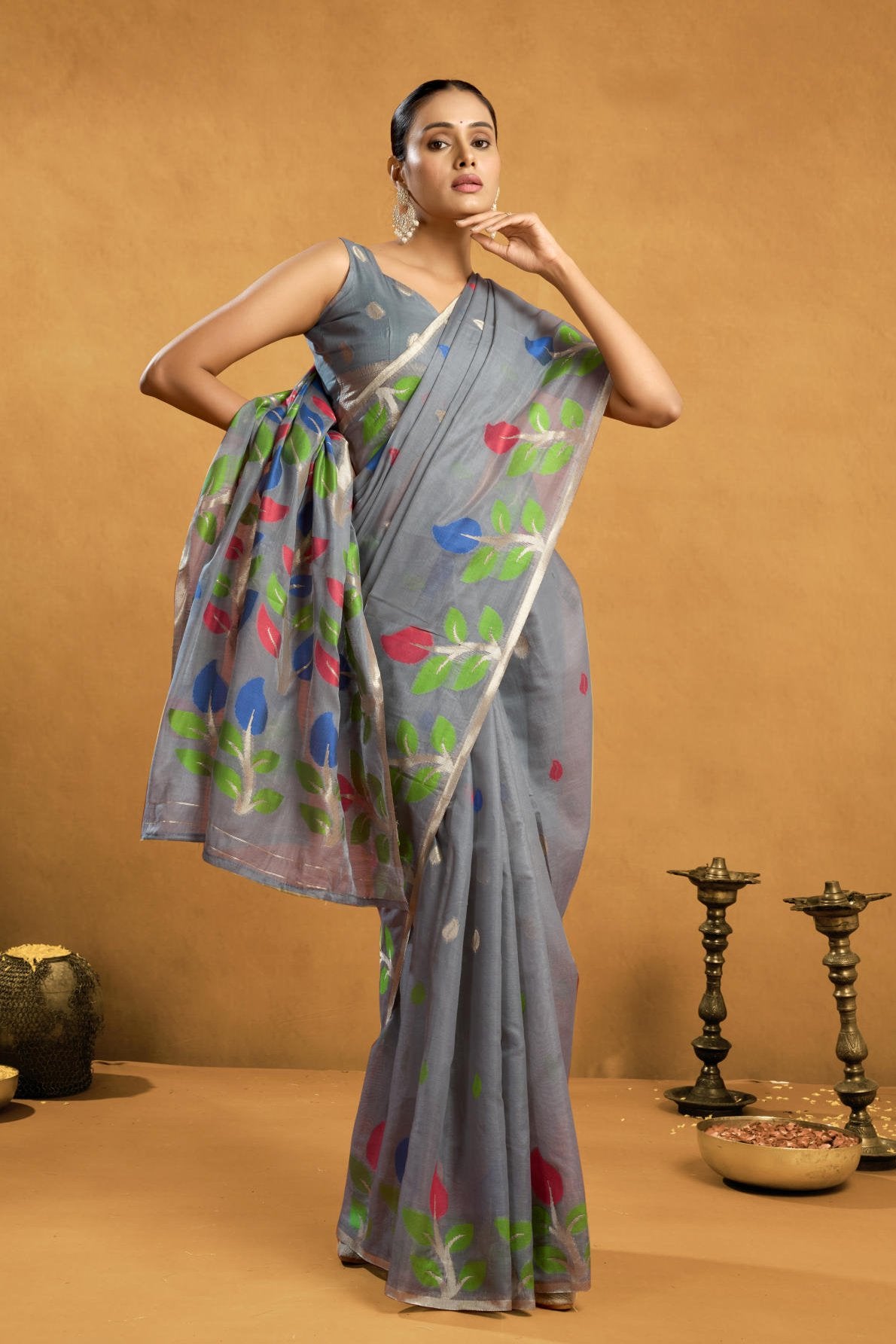 A Pure Cotton Spun Saree featuring exquisite all-over floral Jamdani weaving. The saree is accompanied by a running blouse piece detailed with all-over leaf weave butties and a matching border, available as a six-piece set.
