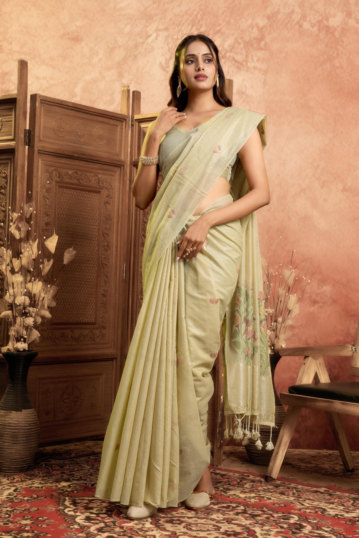 A Pure Cotton Spun Saree featuring delicate, traditional floral Jamdani weaving throughout the body. The pallu is accentuated with an elegant Zari weave border, and it comes with a running blouse piece that includes a matching floral weave border, sold as a six-piece set.