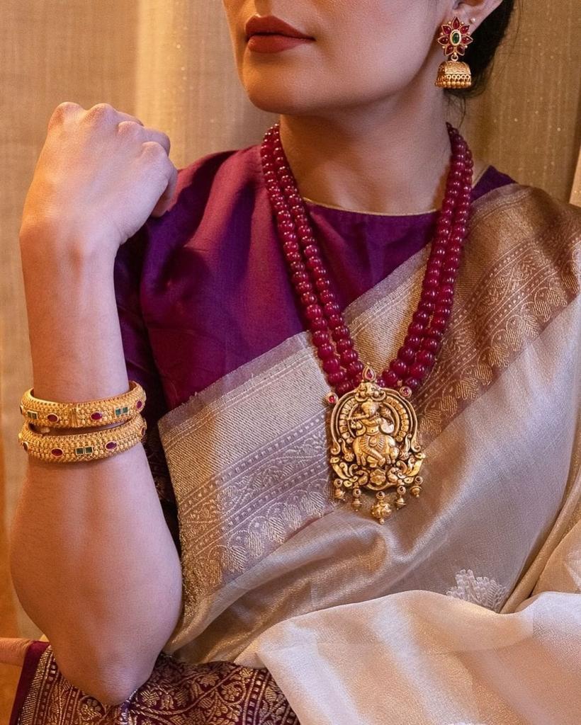 Woman wearing a traditional saree with jewelry, including a necklace and earrings.