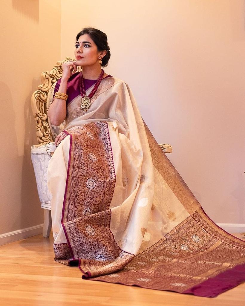 Woman in a traditional saree sitting on a chair indoors.