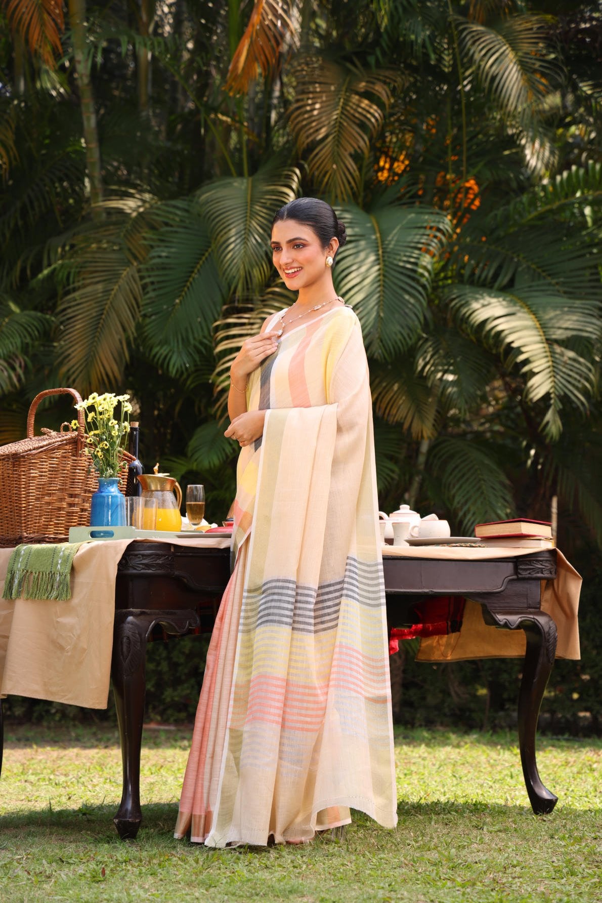 Linen silk saree, multicolor stripes, zari border, contrast blouse, weaving concept, handloom saree, Indian ethnic wear, traditional attire, women's fashion, elegant saree, summer saree, outdoor photoshoot, garden setting, model wearing saree, designer saree, striped saree, lightweight saree, breathable fabric, ethnic fashion, traditional Indian saree.