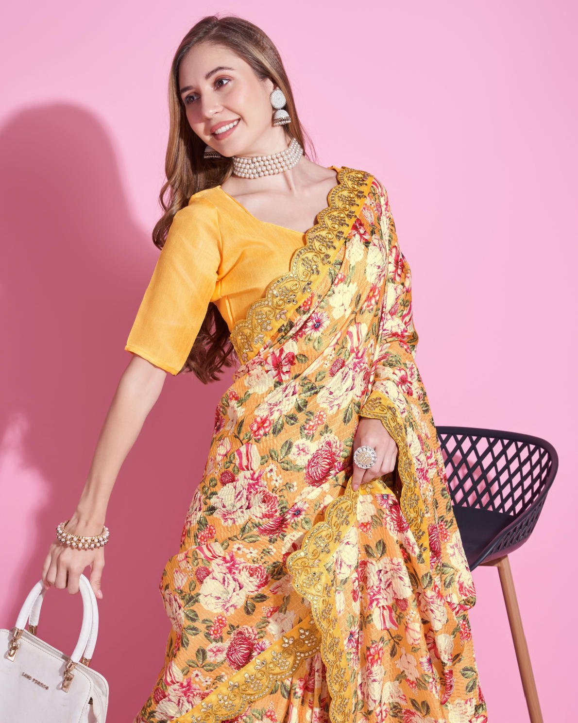 Yellow Vichitra Silk Saree with floral digital print and Zari Dori embroidered border worn by model holding white handbag