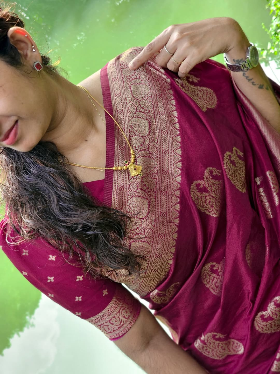 Woman wearing a pink saree with intricate patterns against a green background