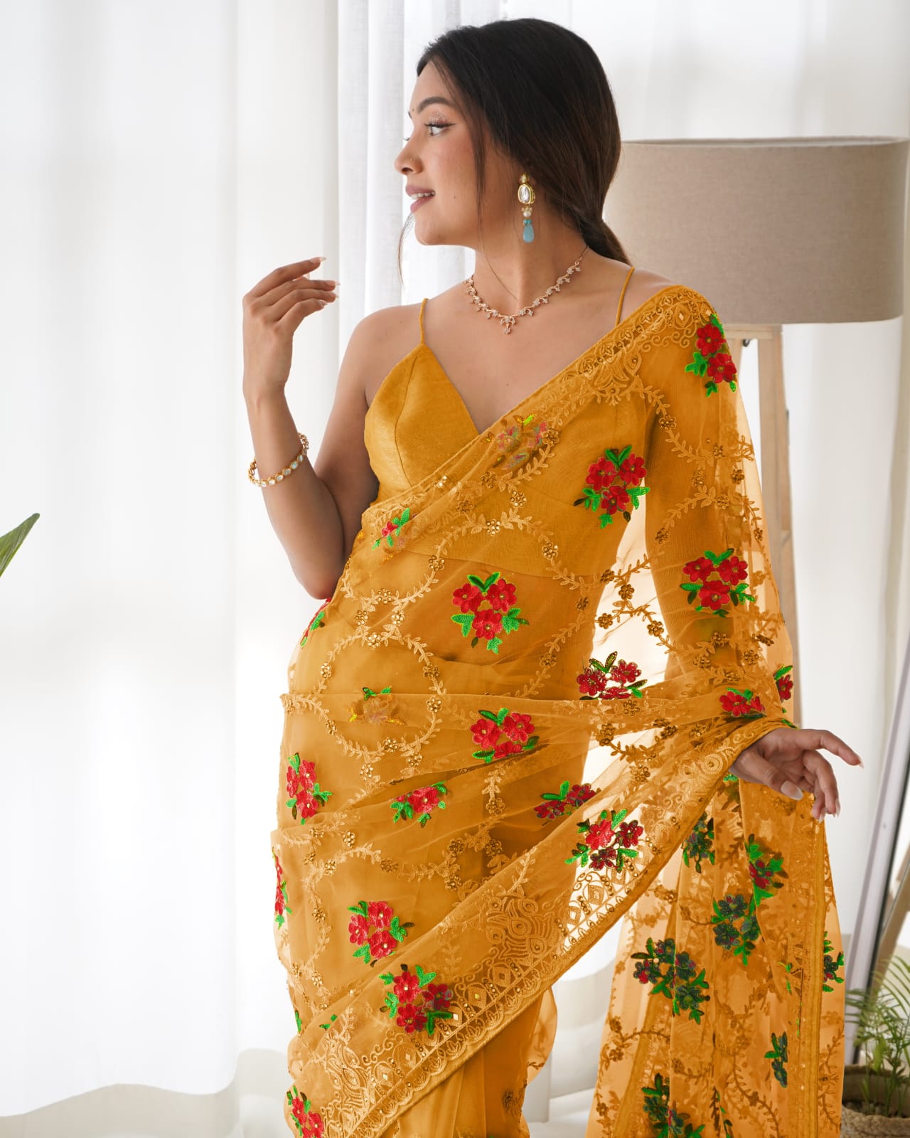 Mustard yellow heavy butterfly net saree with red and green floral aari embroidery and stone work
