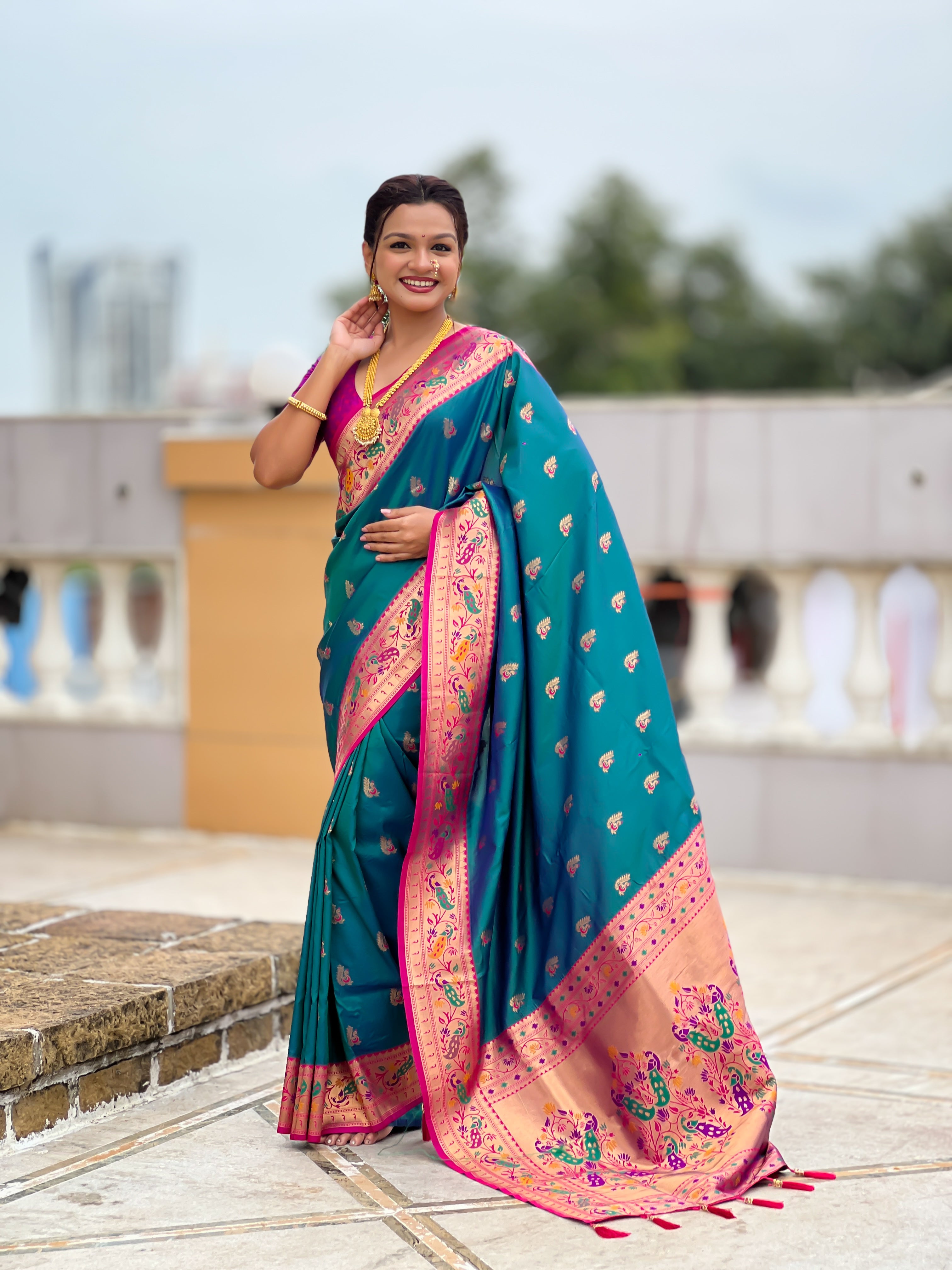 Model wearing a royal soft Paithani silk saree with Meenakari zari weaving and contrast pink border in a traditional temple setting
