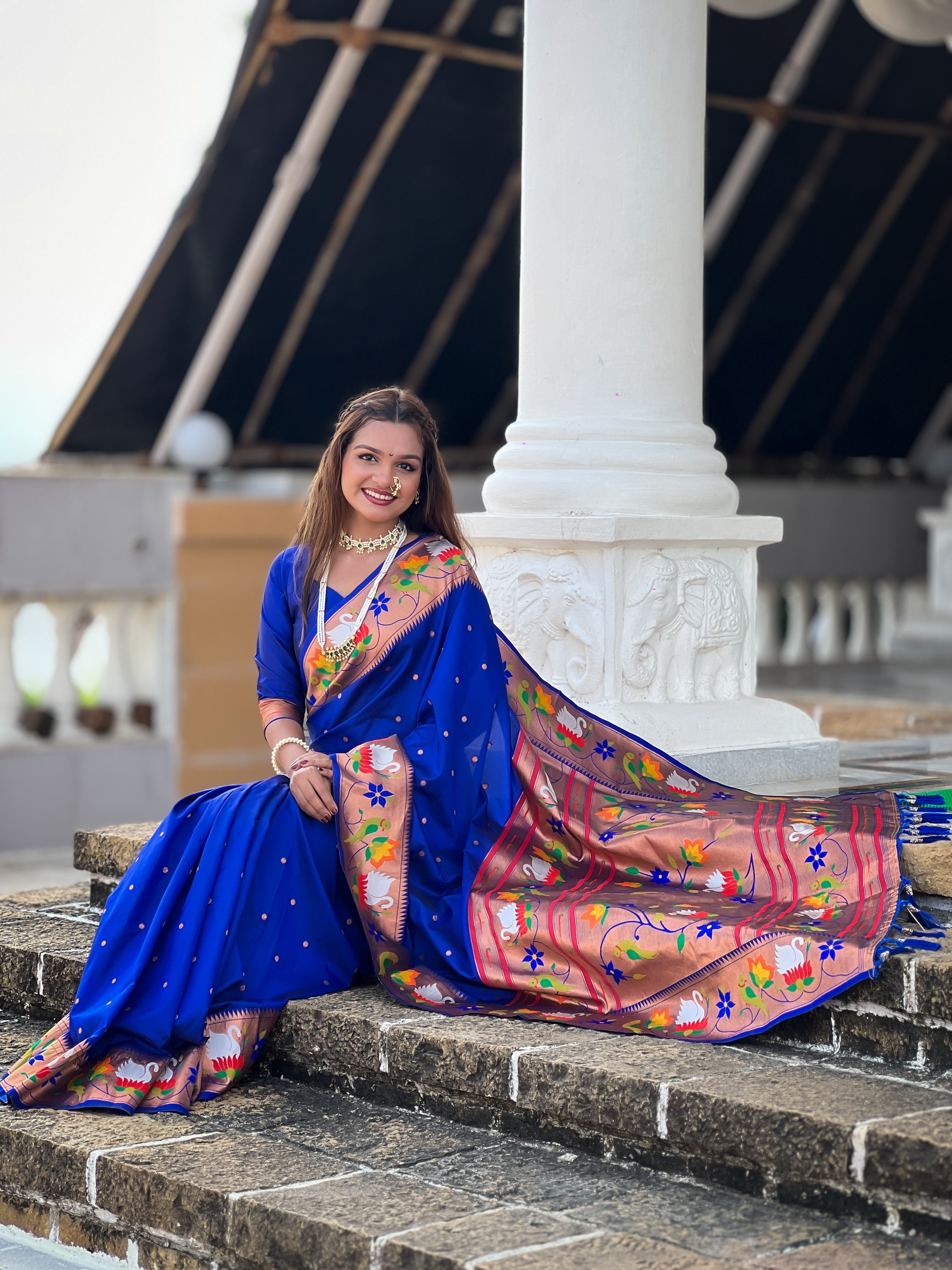Model wearing N Blue soft paithani silk saree with colorful meenakari floral border and gold zari pallu