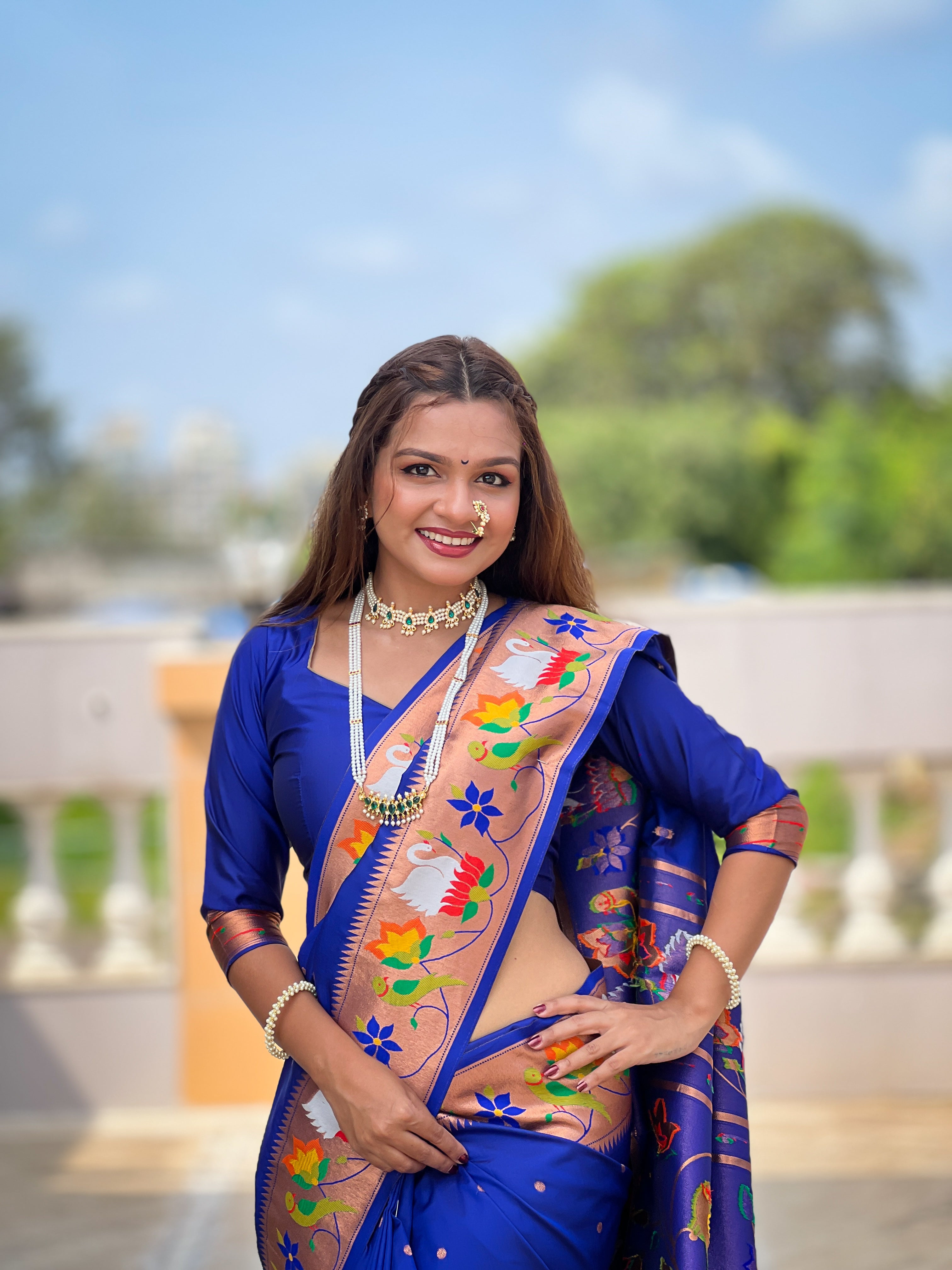 Model wearing N Blue soft paithani silk saree with colorful meenakari floral border and gold zari pallu