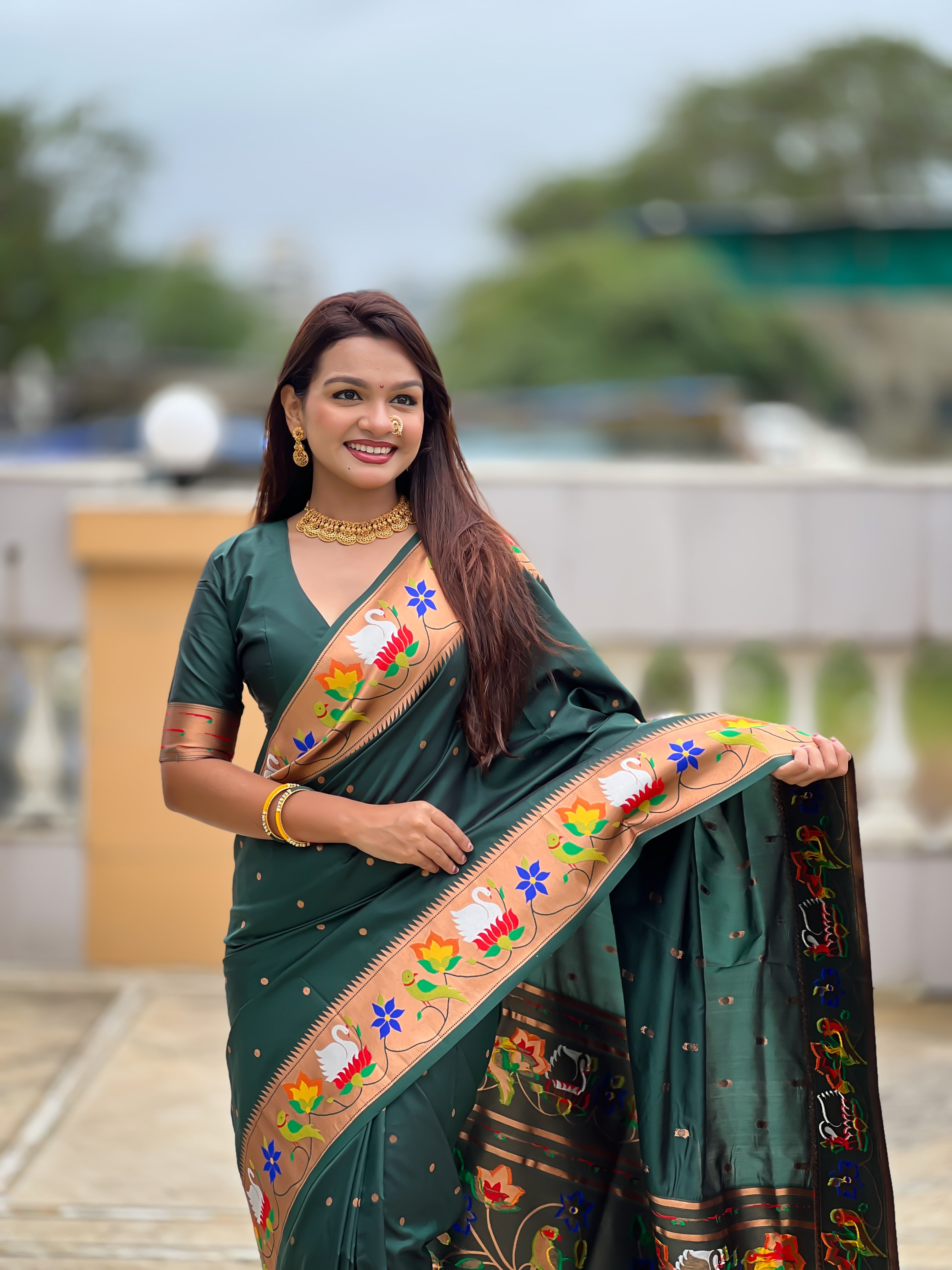 Model wearing bottle green soft paithani silk saree with colorful meenakari floral border and gold zari pallu