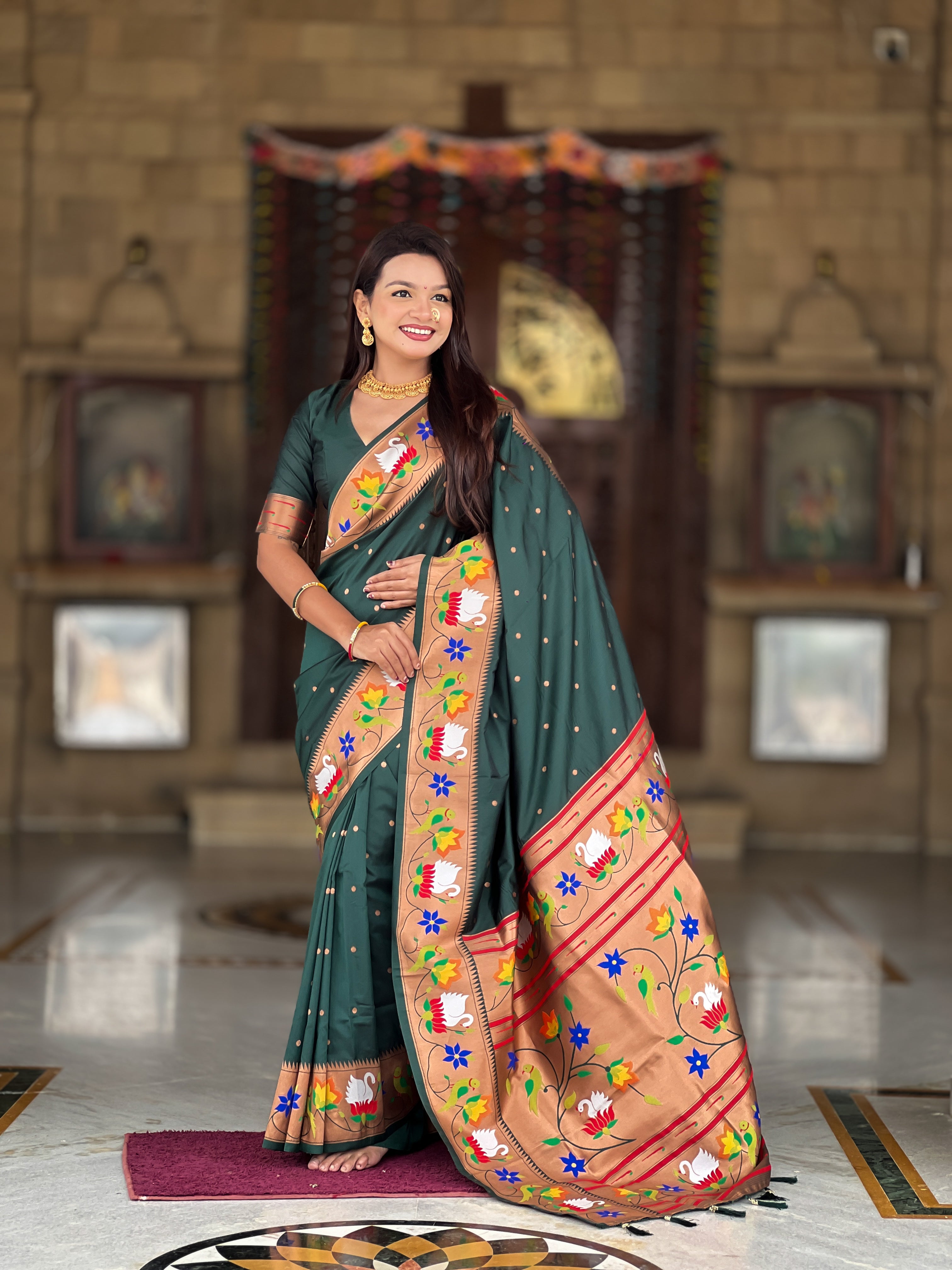 Model wearing bottle green soft paithani silk saree with colorful meenakari floral border and gold zari pallu