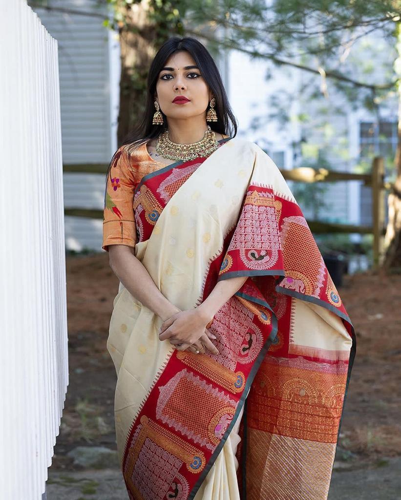 Woman wearing a traditional saree with a red and gold pattern, standing outdoors.