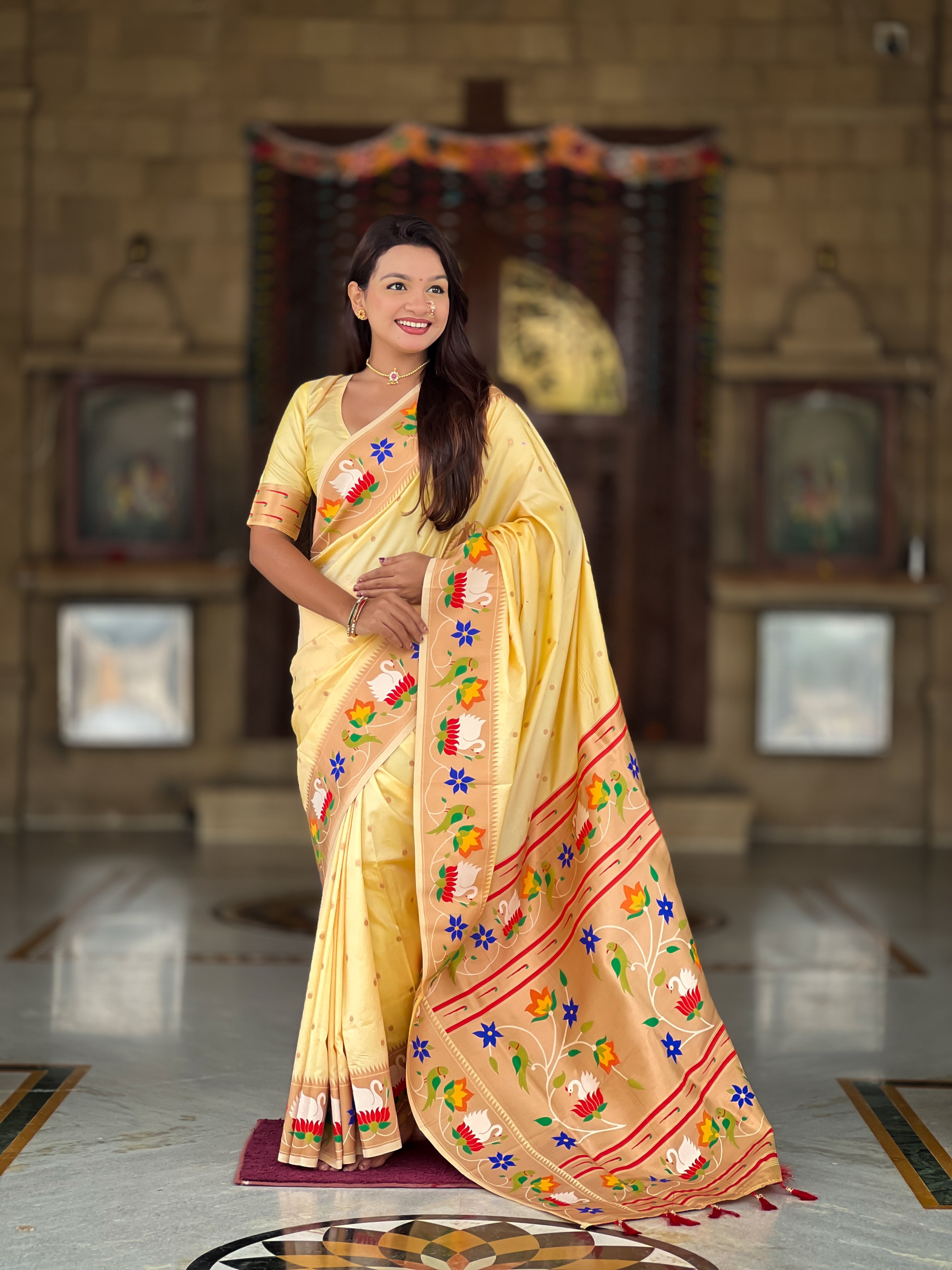 Model wearing Cream soft paithani silk saree with colorful meenakari floral border and gold zari pallu