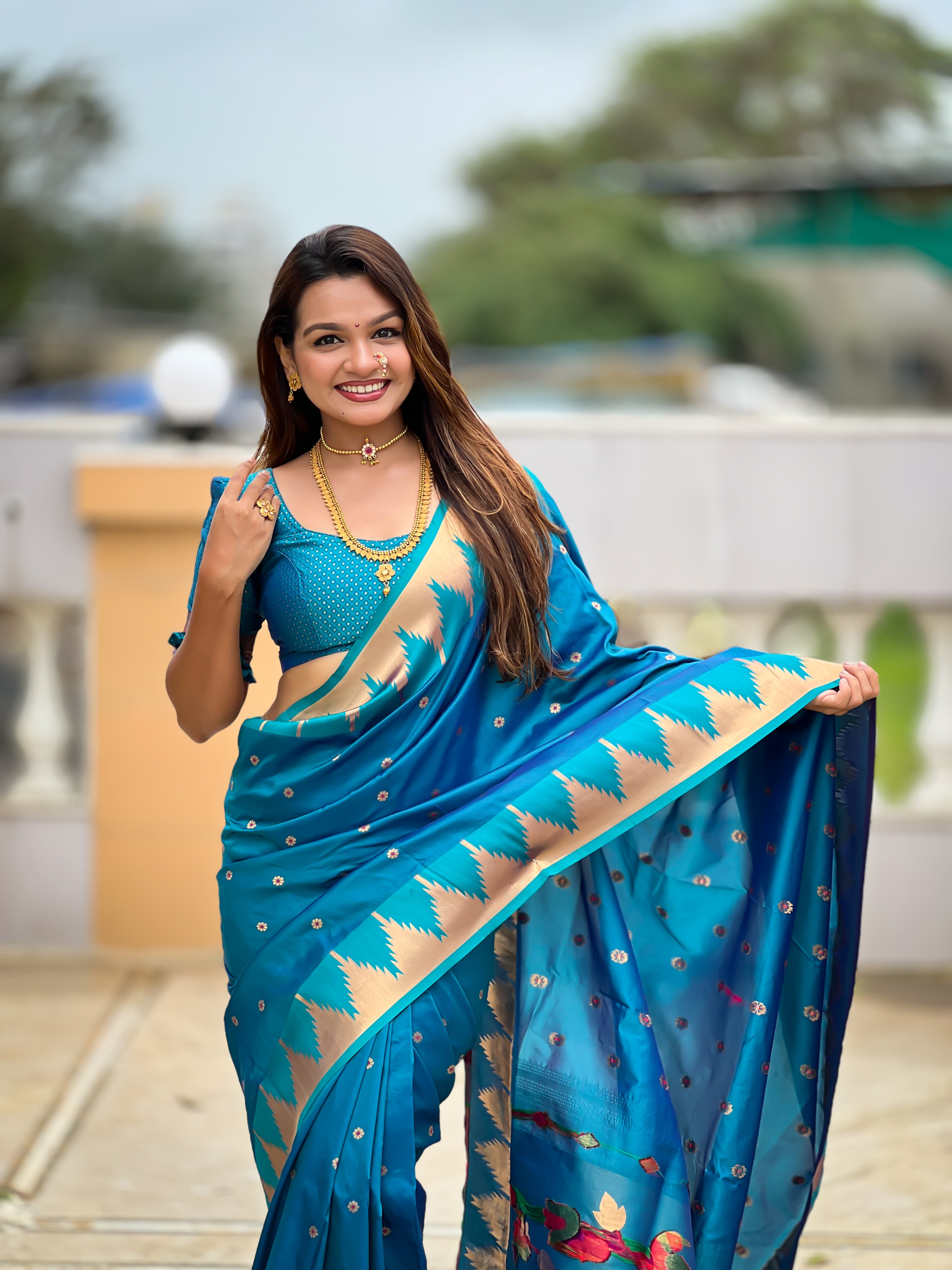 Firozi blue soft Paithani silk saree with Meenakari pallu and temple border worn by a model in a traditional setting