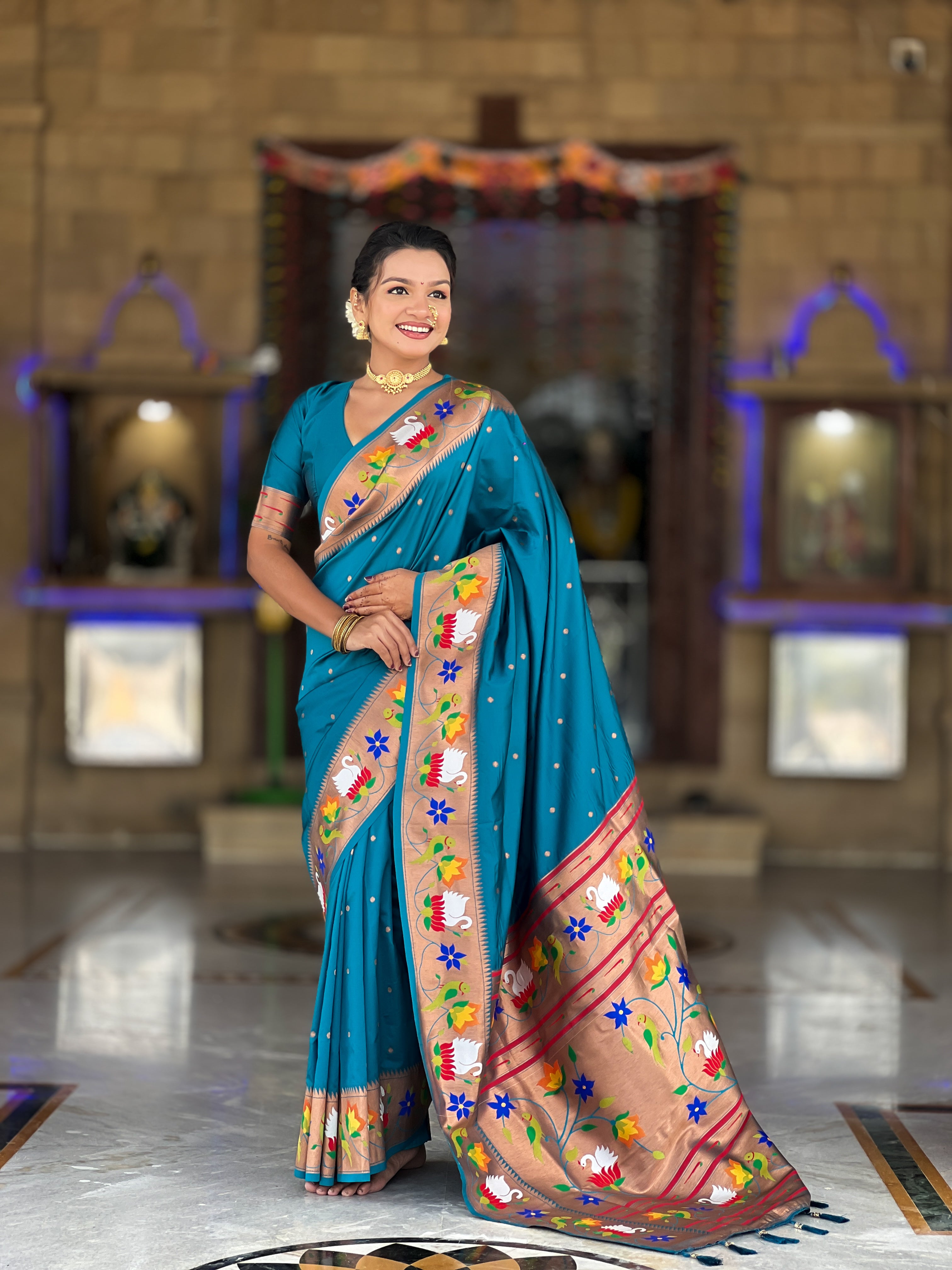 Model wearing Firozi soft paithani silk saree with colorful meenakari floral border and gold zari pallu