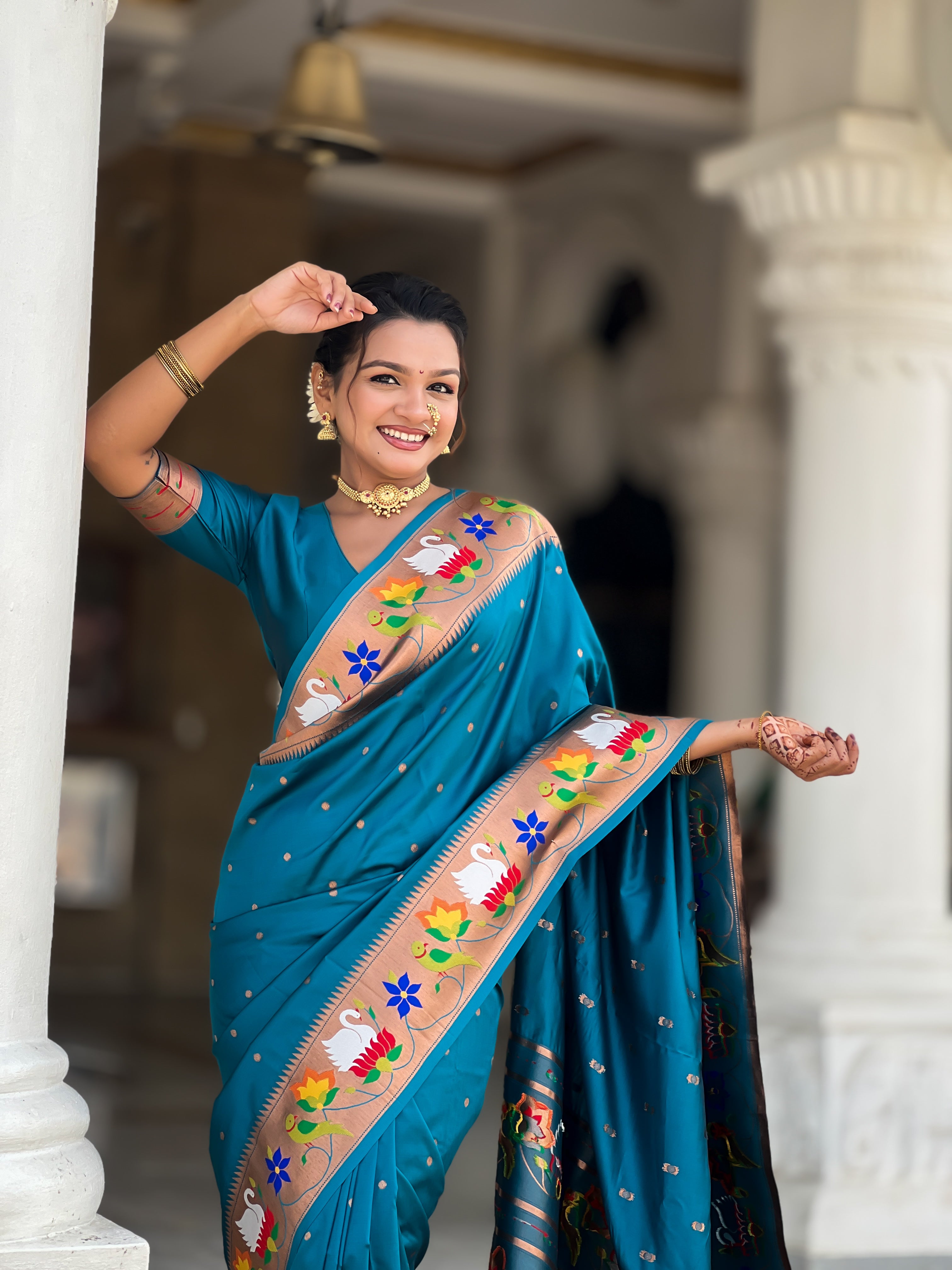 Model wearing Firozi soft paithani silk saree with colorful meenakari floral border and gold zari pallu