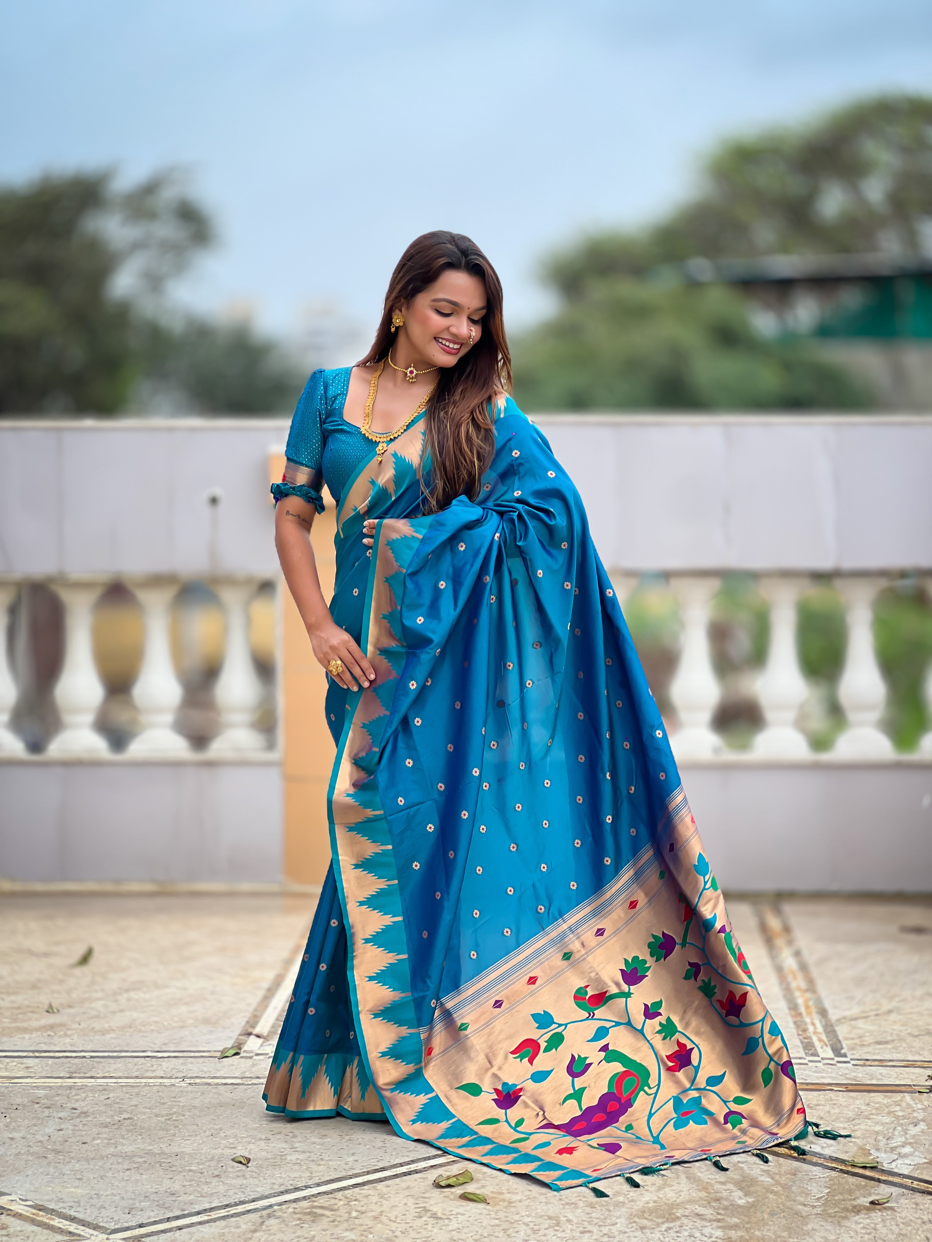 Firozi blue soft Paithani silk saree with Meenakari pallu and temple border worn by a model in a traditional setting