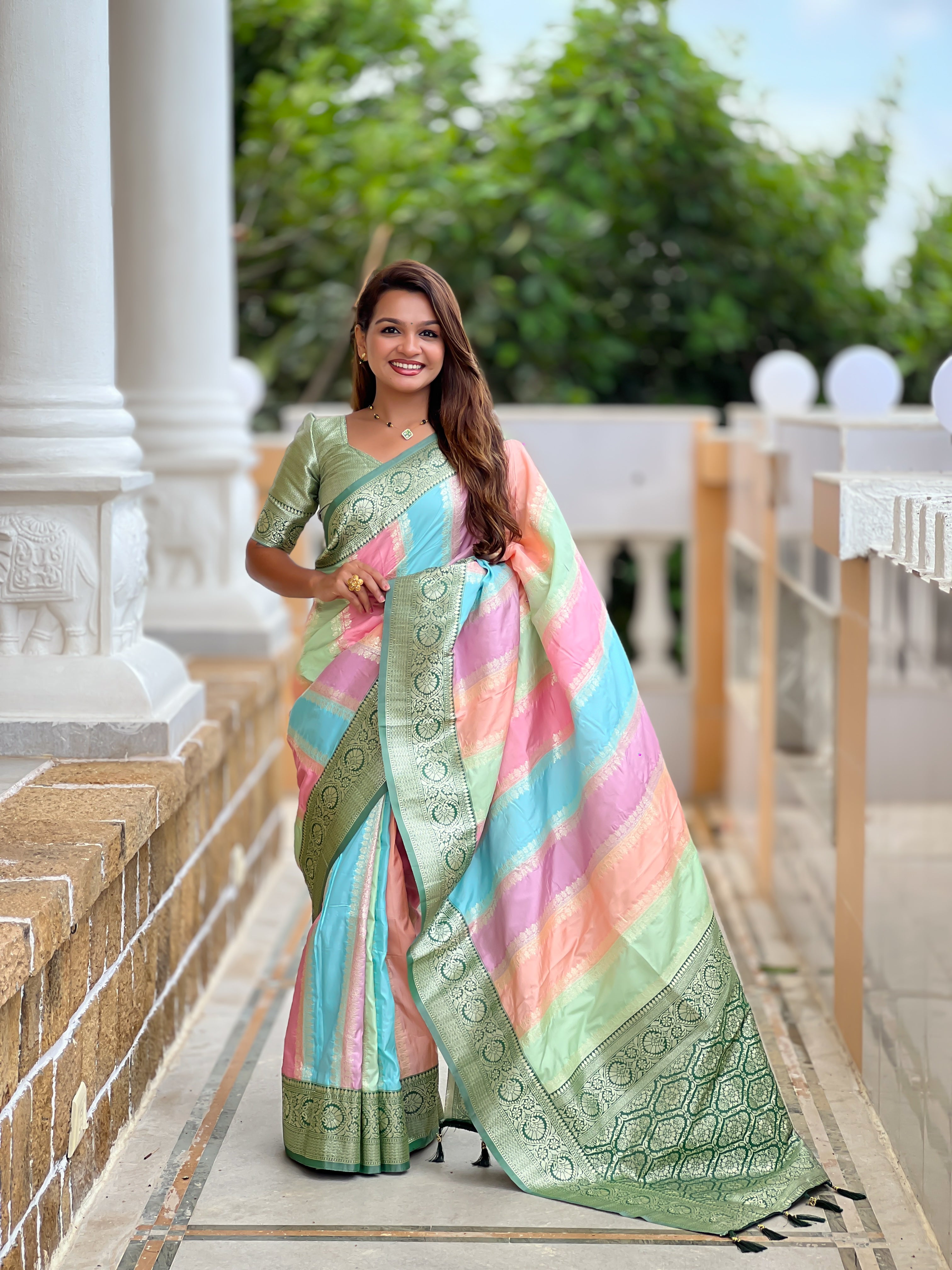 Woman wearing multi-colored pastel soft silk saree with intricate green zari border and Meenakari weaving details