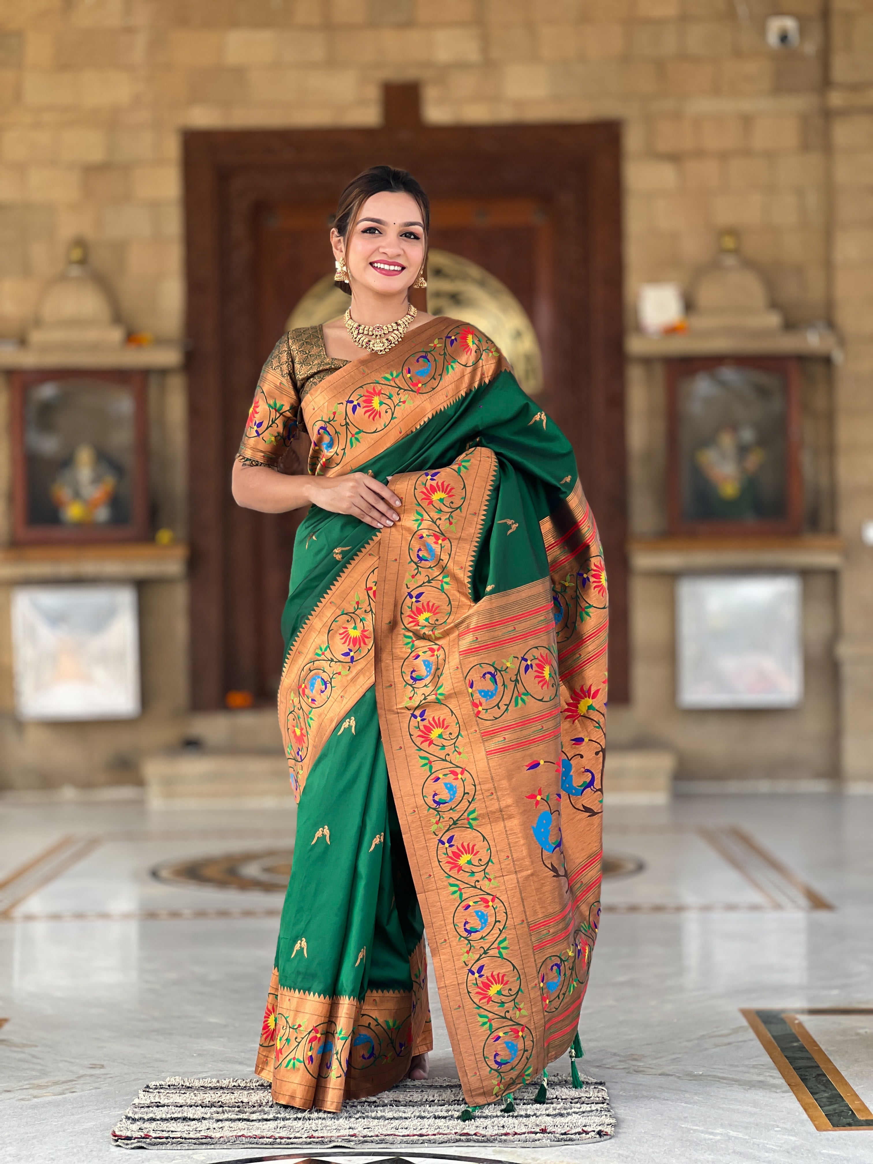 Model wearing Royal Green Soft Paithani Silk Saree with gold Zari weaving and colorful Meenakari peacock motifs