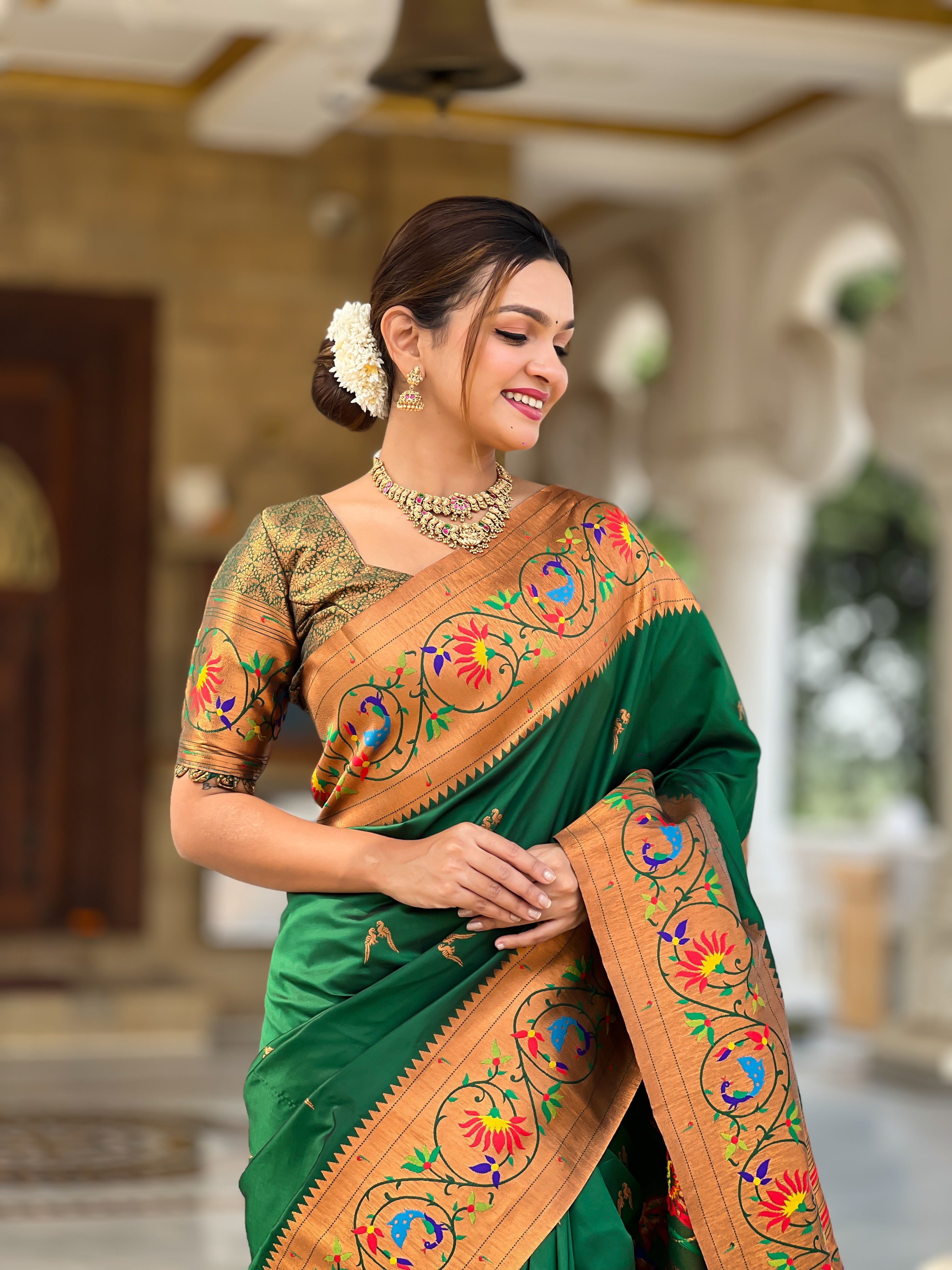Model wearing Royal Green Soft Paithani Silk Saree with gold Zari weaving and colorful Meenakari peacock motifs