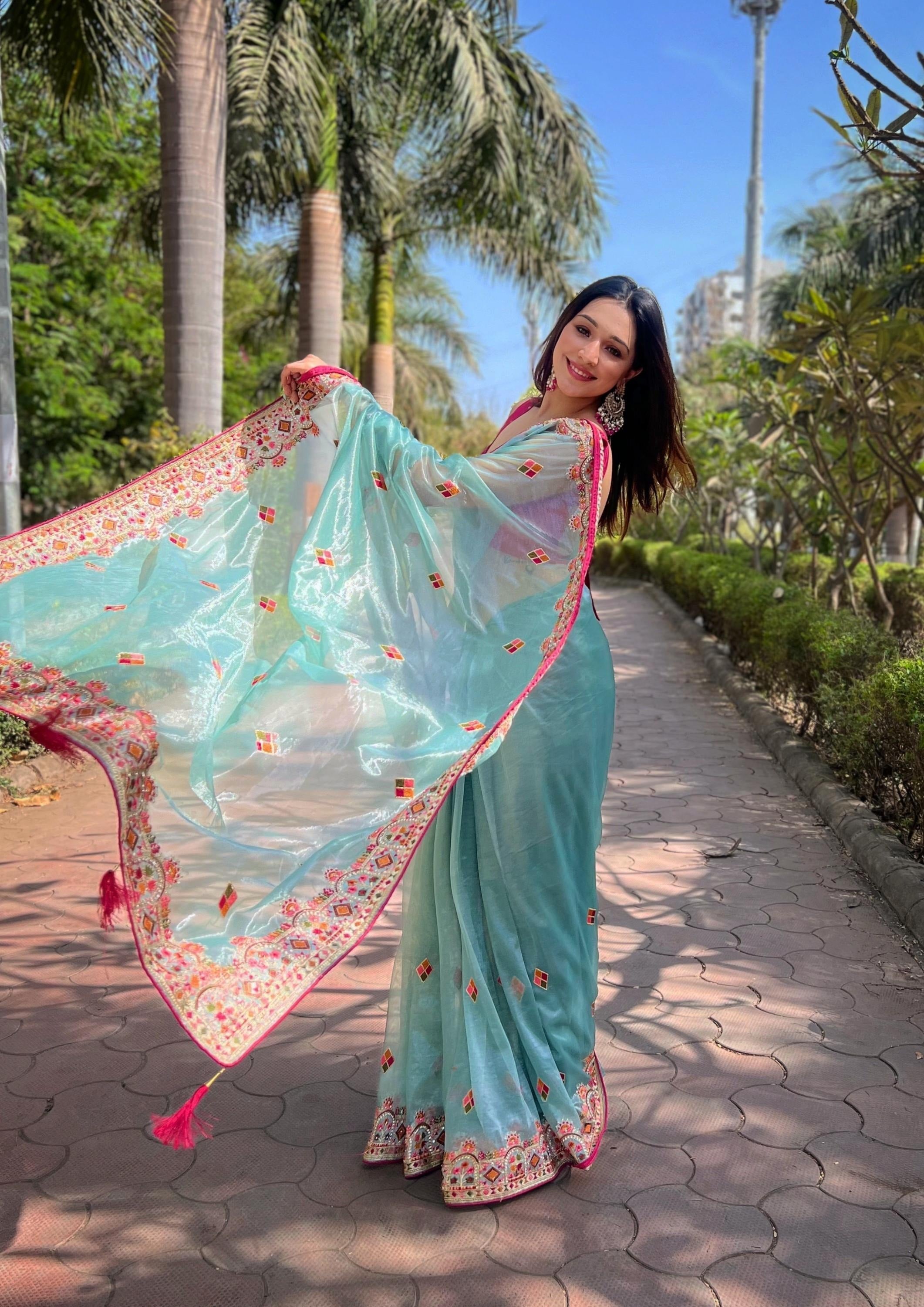 Woman wearing shimmering aqua silver tissue silk saree with pink jari dori embroidery and diamond work