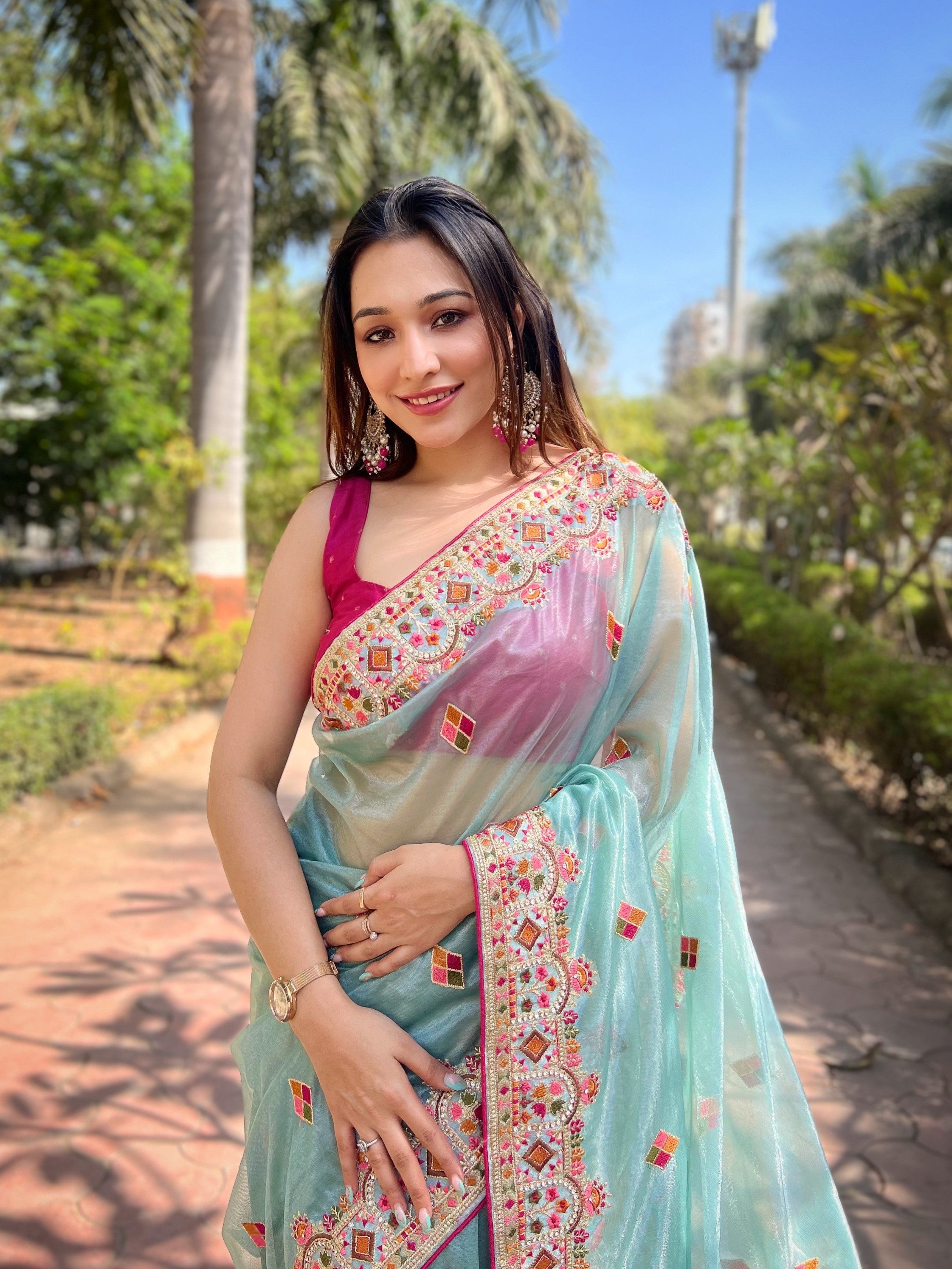 Woman wearing shimmering aqua silver tissue silk saree with pink jari dori embroidery and diamond work