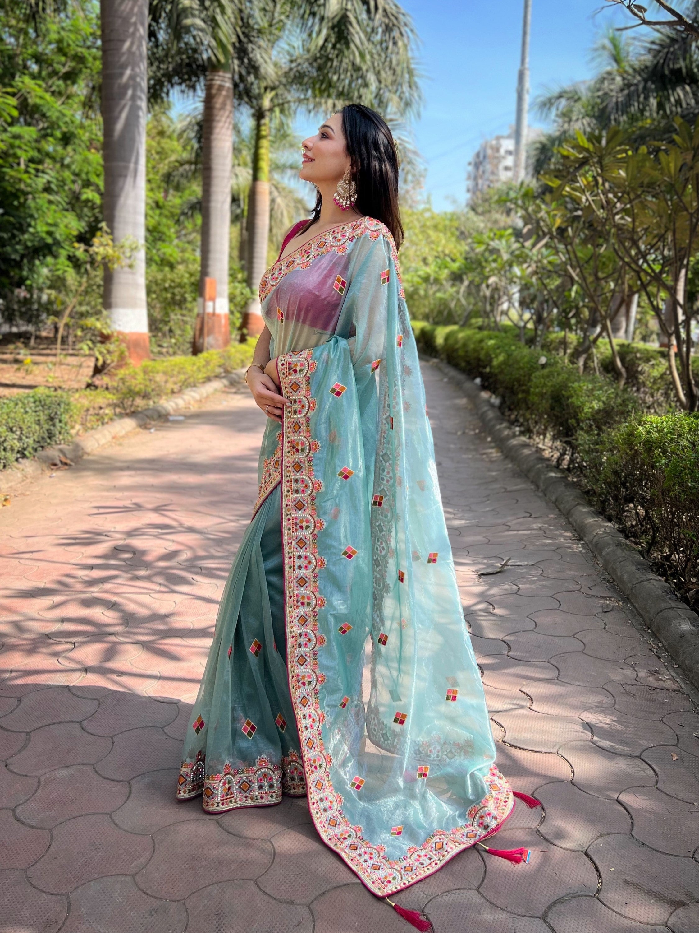 Woman wearing shimmering aqua silver tissue silk saree with pink jari dori embroidery and diamond work