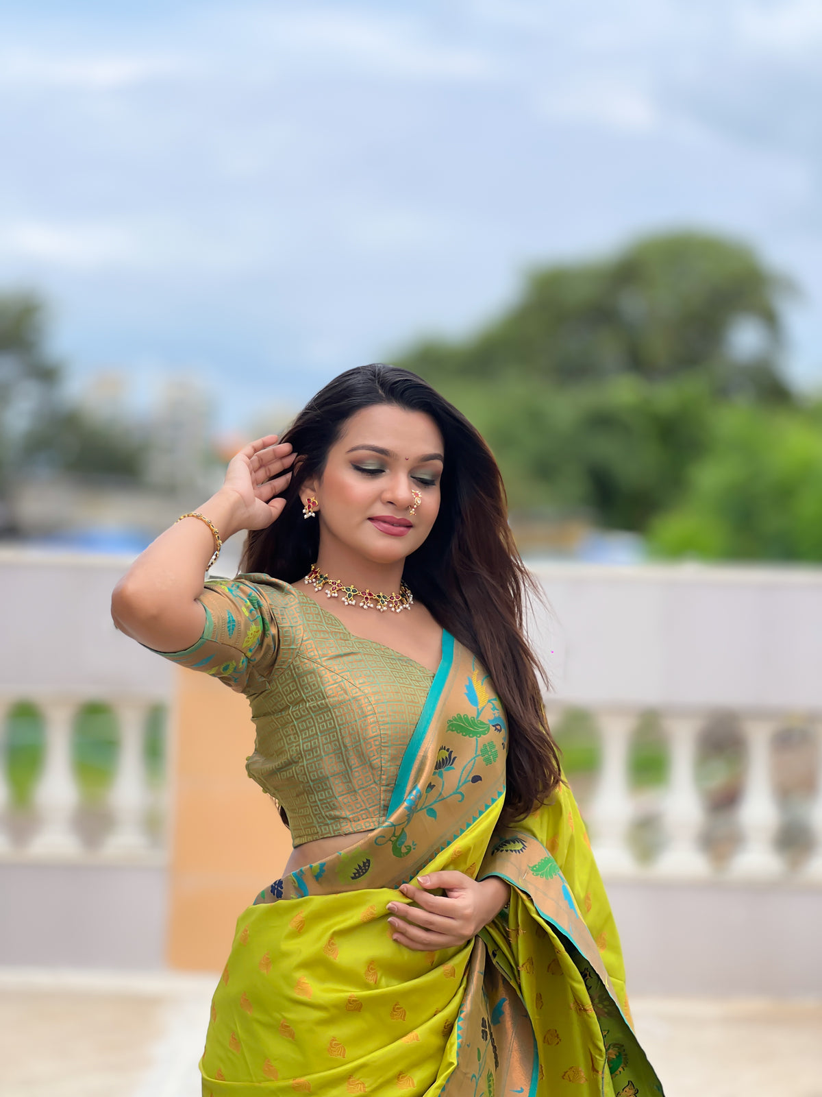 Woman wearing a lime green soft Paithani silk saree with blue and gold Meenakari peacock border and rich zari pallu