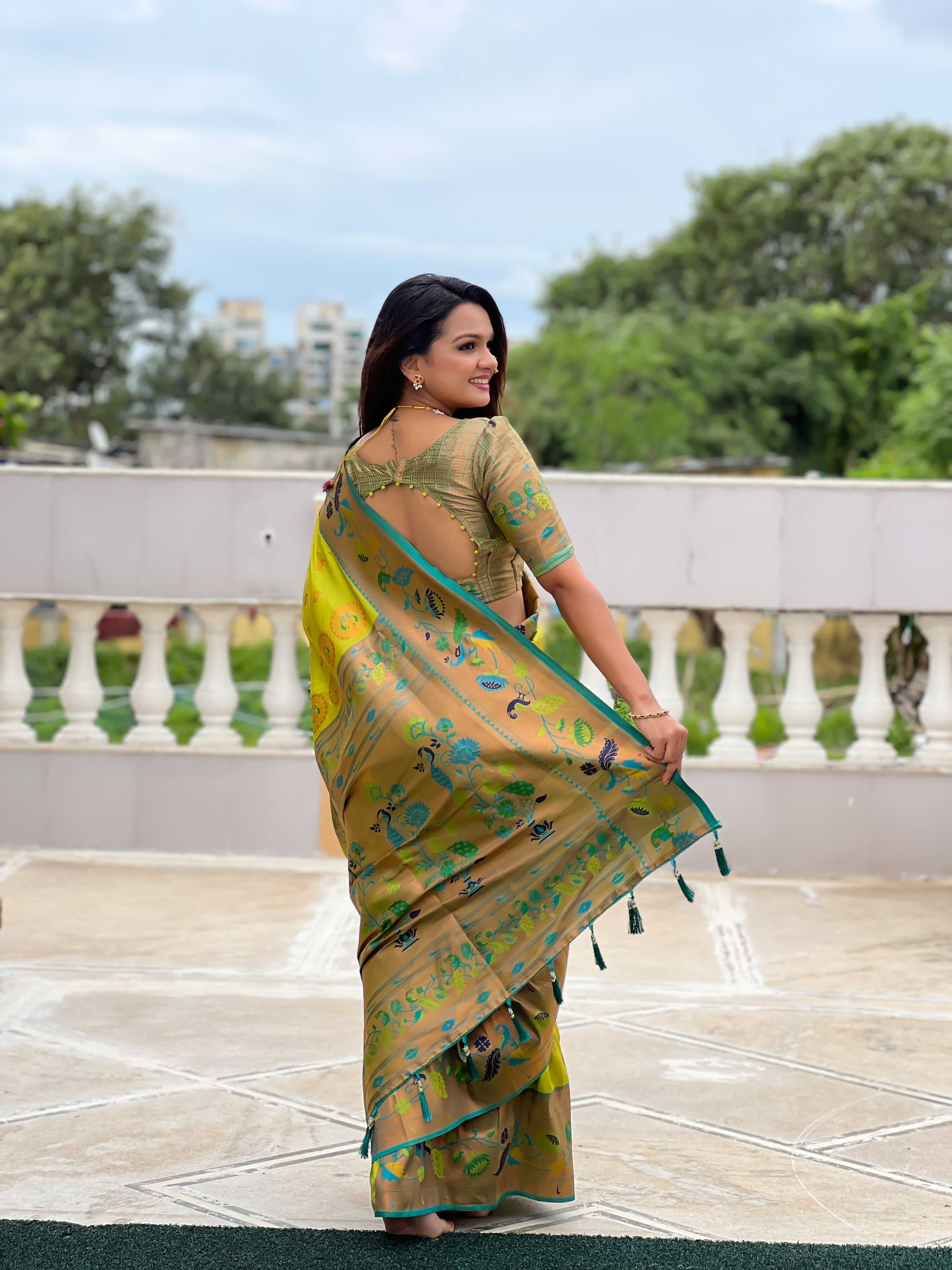 Woman wearing a lime green soft Paithani silk saree with blue and gold Meenakari peacock border and rich zari pallu