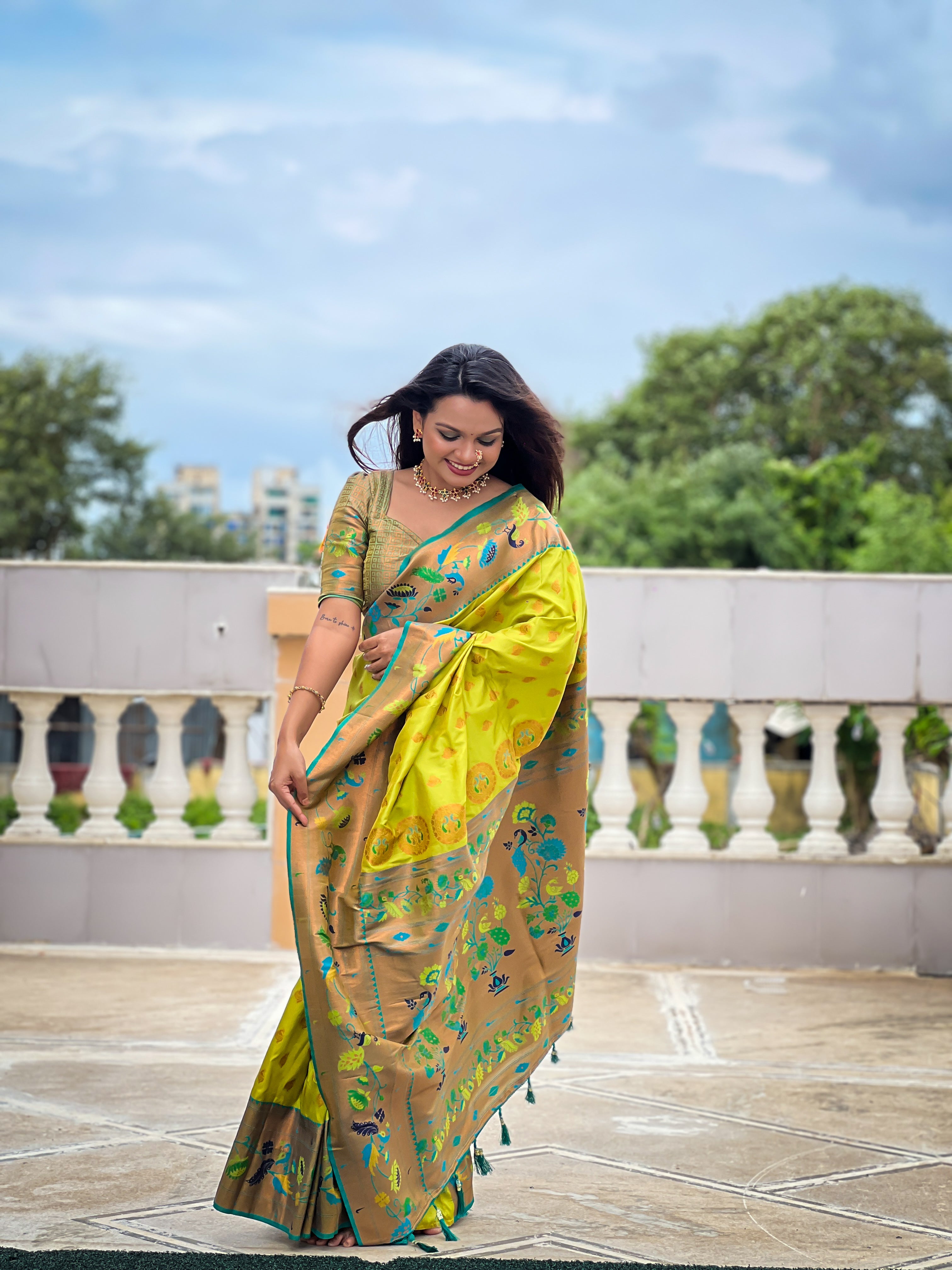 Woman wearing a lime green soft Paithani silk saree with blue and gold Meenakari peacock border and rich zari pallu