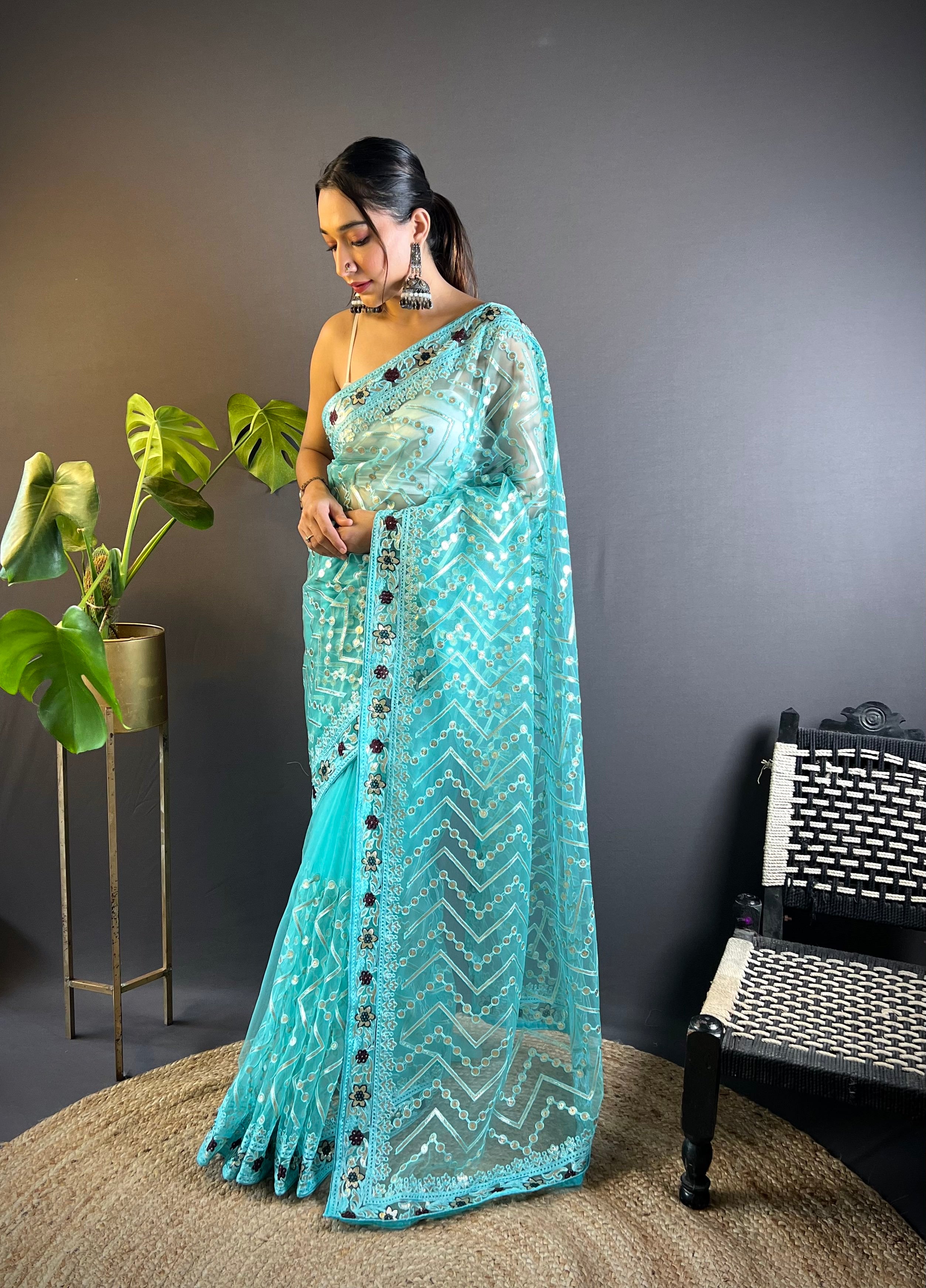 Model wearing a sheer butterfly net saree with geometric chain stitch embroidery, foil thread work, and heavy stone embellished border