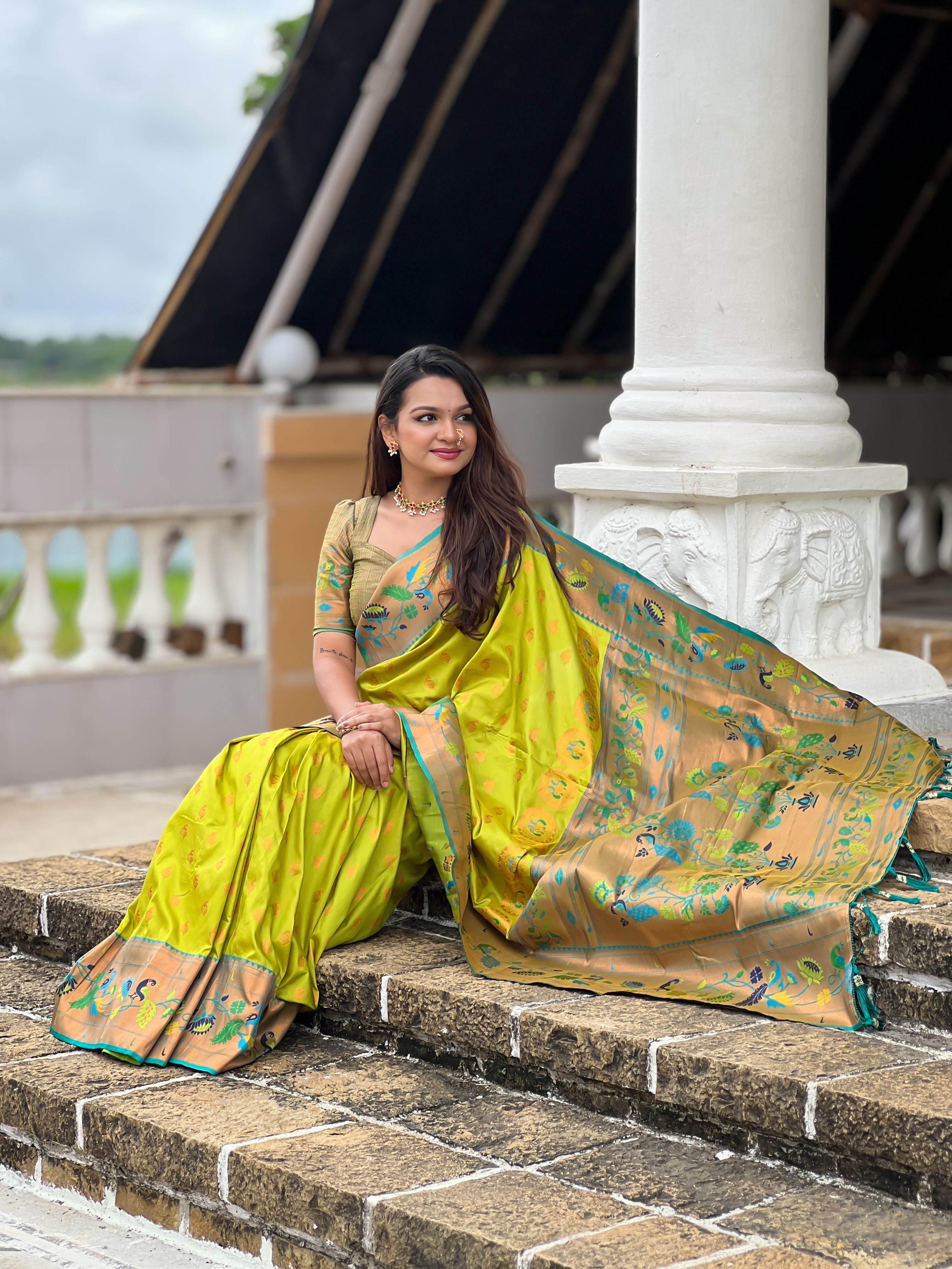 Woman wearing a lime green soft Paithani silk saree with blue and gold Meenakari peacock border and rich zari pallu