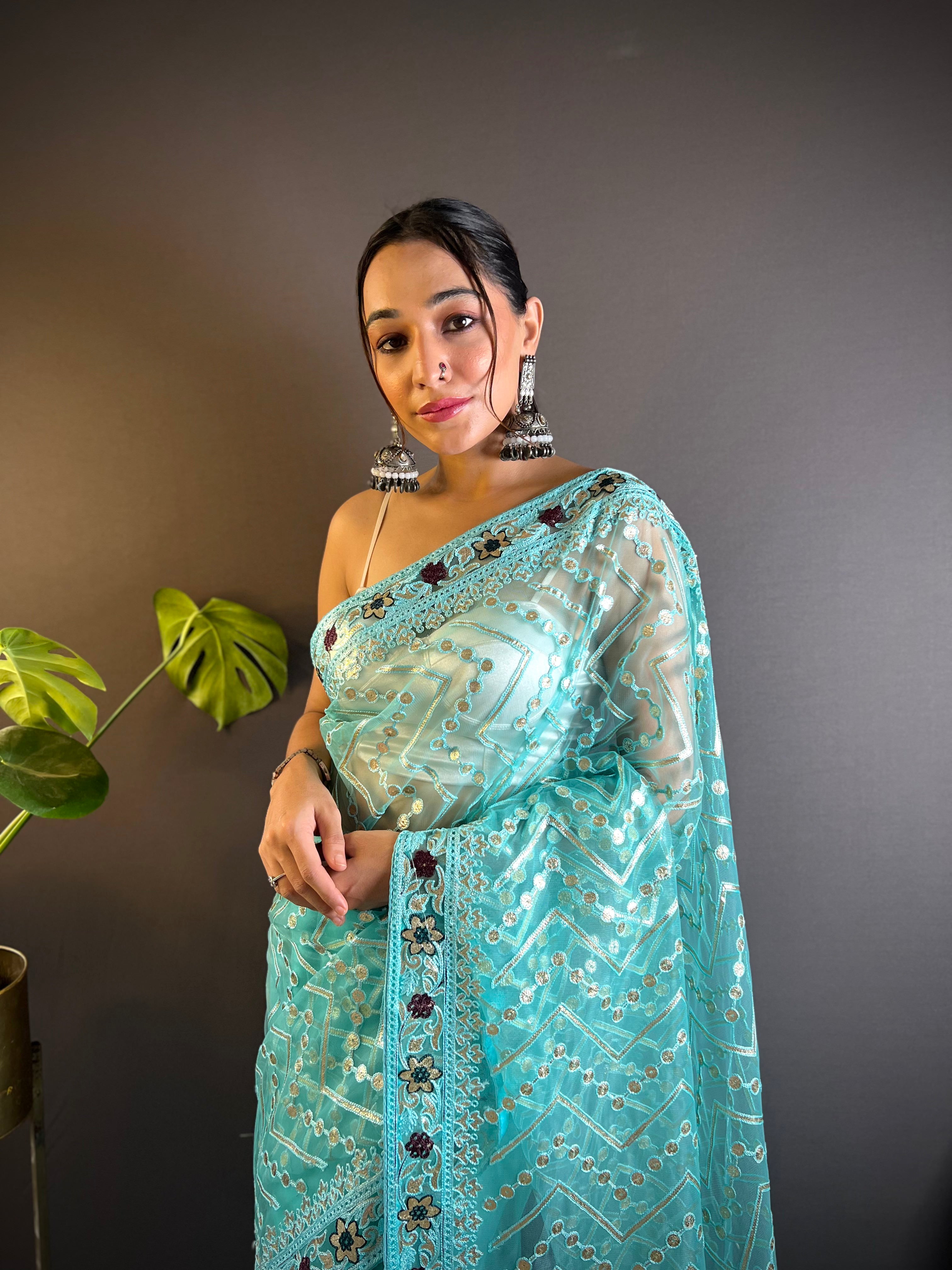 Model wearing a sheer butterfly net saree with geometric chain stitch embroidery, foil thread work, and heavy stone embellished border